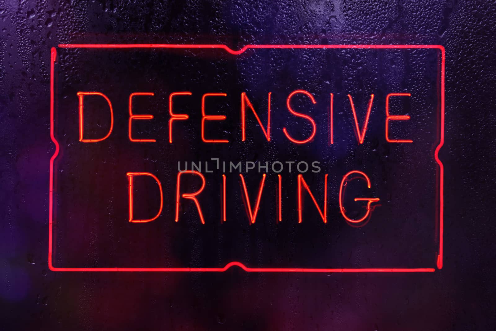 Neon Defensive Driving Sign in Wet Window