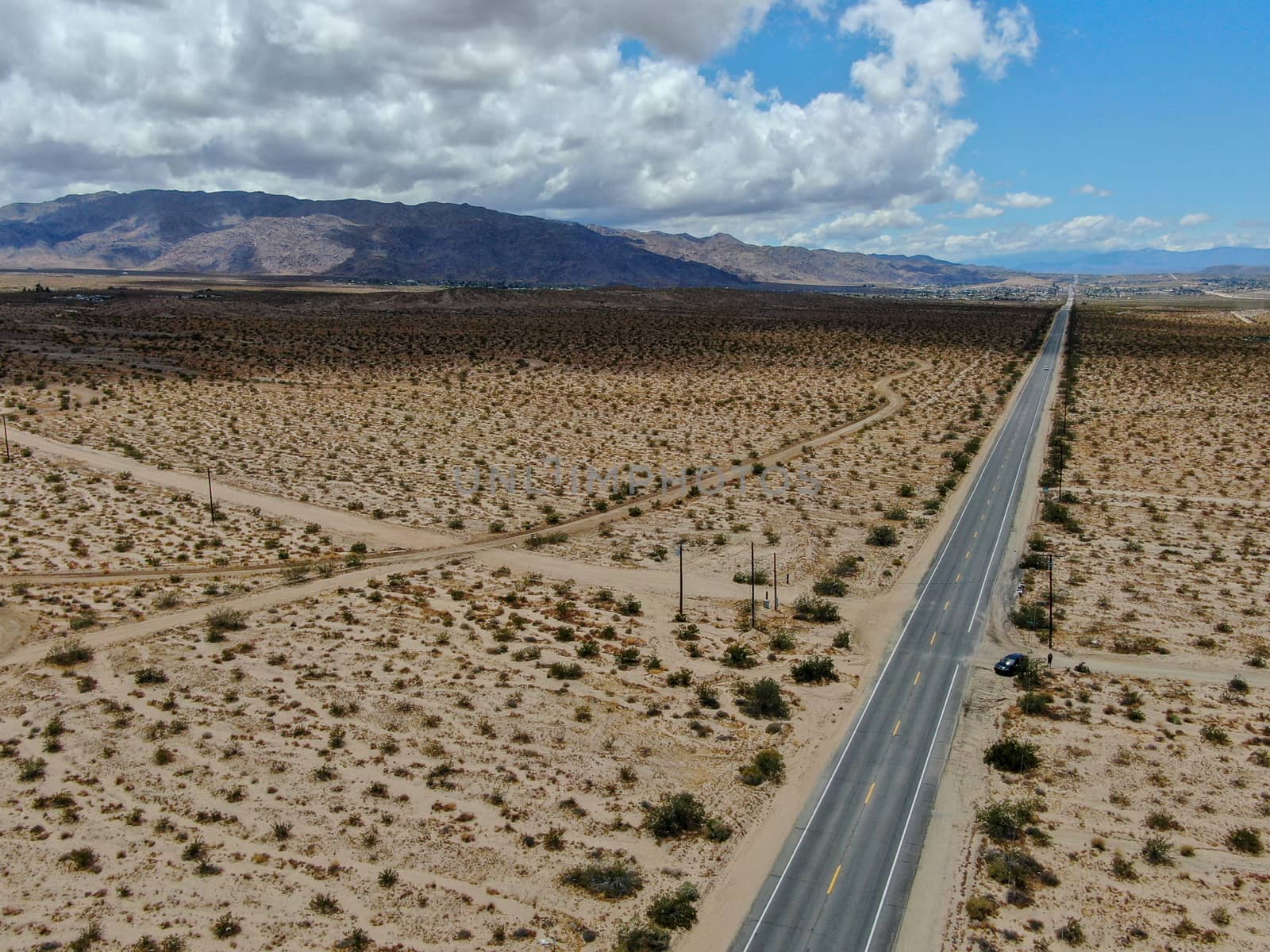 Aerial view of endless desert straight dusty asphalt road in Joshua Tree Park. USA. Long straight tarmac road heading into the desert to the direction of Arizona.