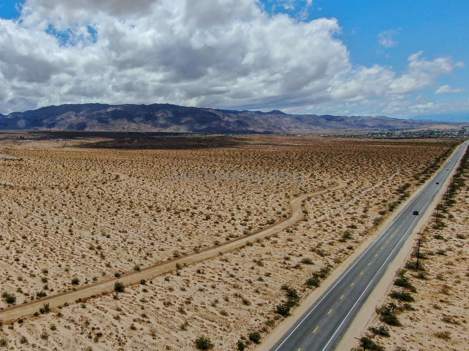 Aerial view of endless desert straight dusty asphalt road in Joshua Tree Park. USA. Long straight tarmac road heading into the desert to the direction of Arizona.