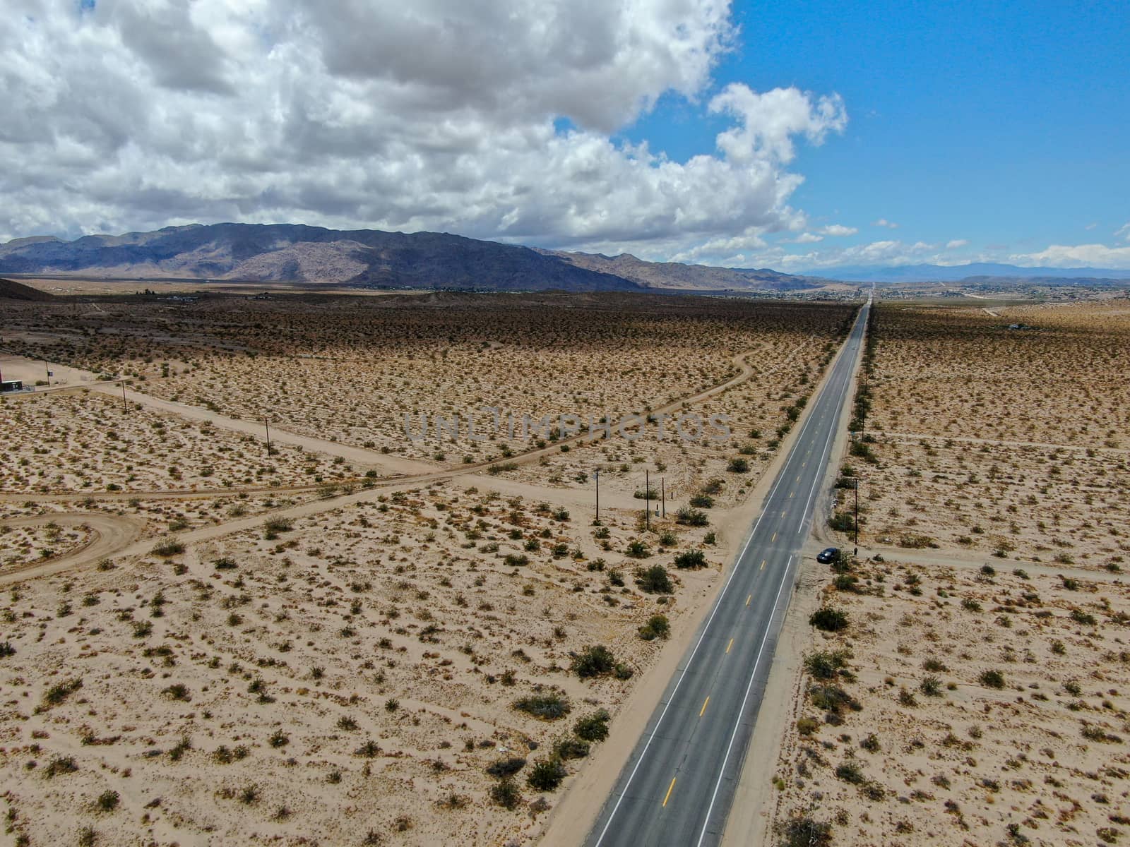 Aerial view of endless desert straight dusty asphalt road in Joshua Tree Park. USA. by Bonandbon