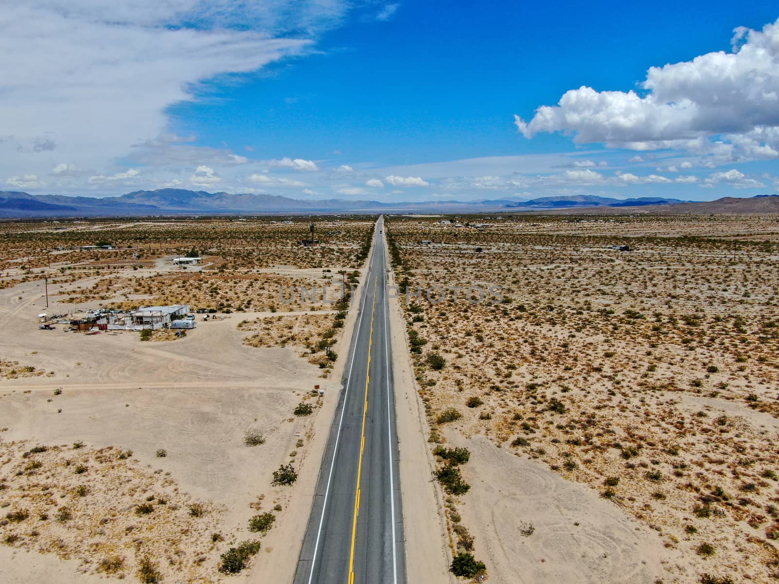 Aerial view of endless desert straight dusty asphalt road in Joshua Tree Park. USA. by Bonandbon