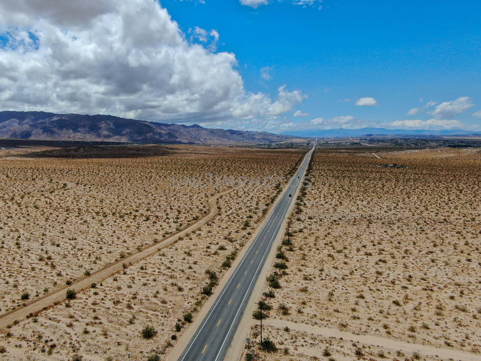 Aerial view of endless desert straight dusty asphalt road in Joshua Tree Park. USA. by Bonandbon