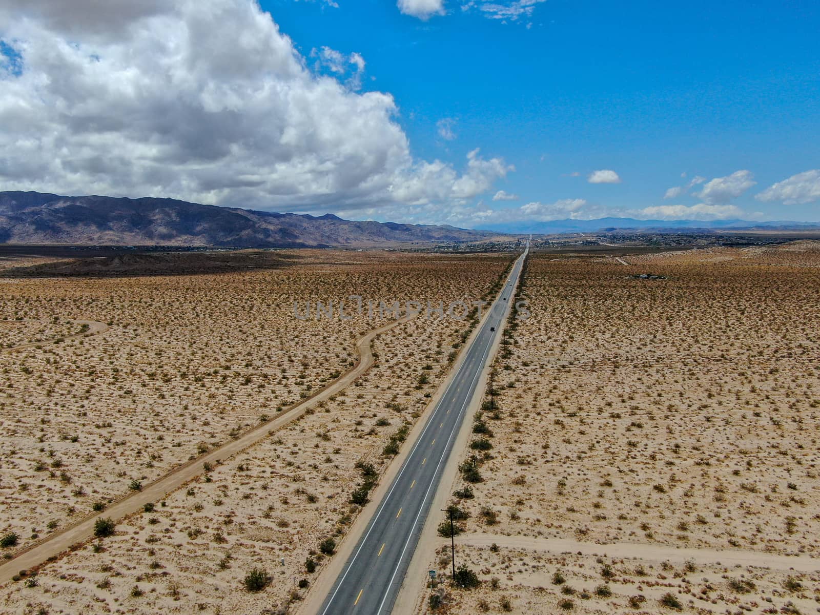 Aerial view of endless desert straight dusty asphalt road in Joshua Tree Park. USA. by Bonandbon