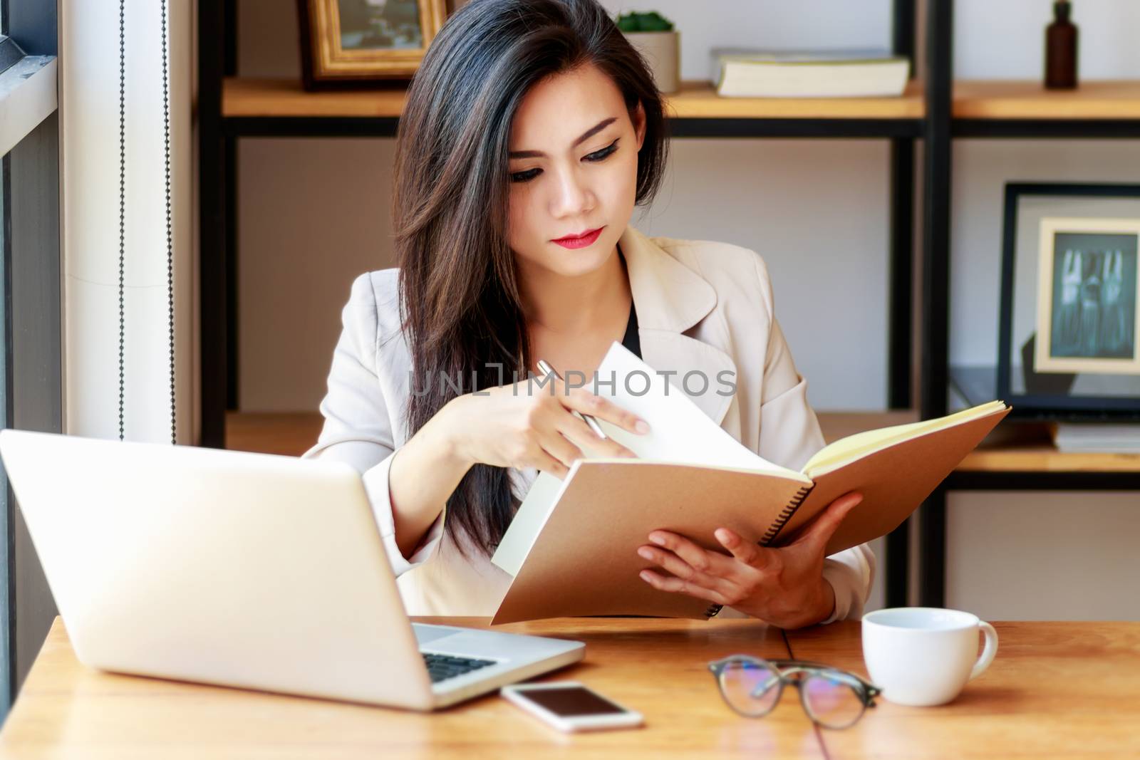 young Asian business woman working at workplace. beautiful Asian woman in casual suit working with reading book, prepare for meeting or interview in modern office. freelance, start up business in Asia by asiandelight