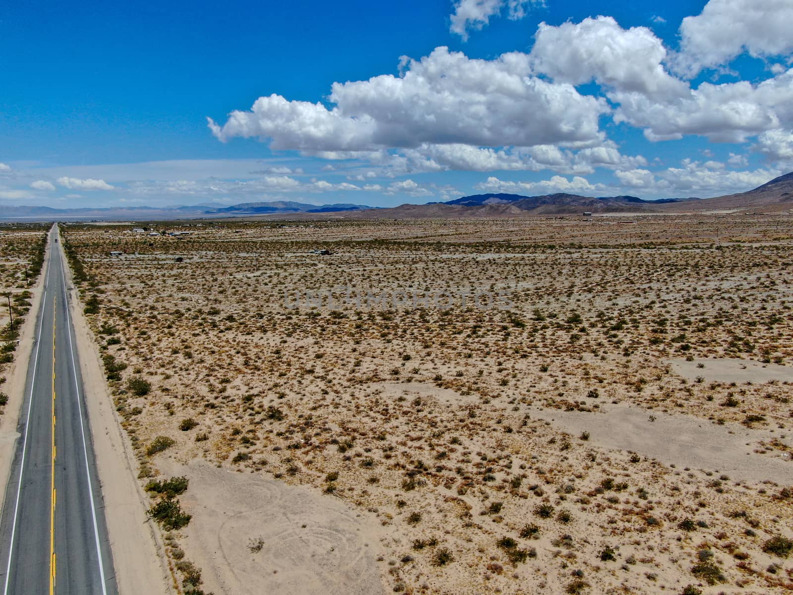 Aerial view of endless desert straight dusty asphalt road in Joshua Tree Park. USA. by Bonandbon