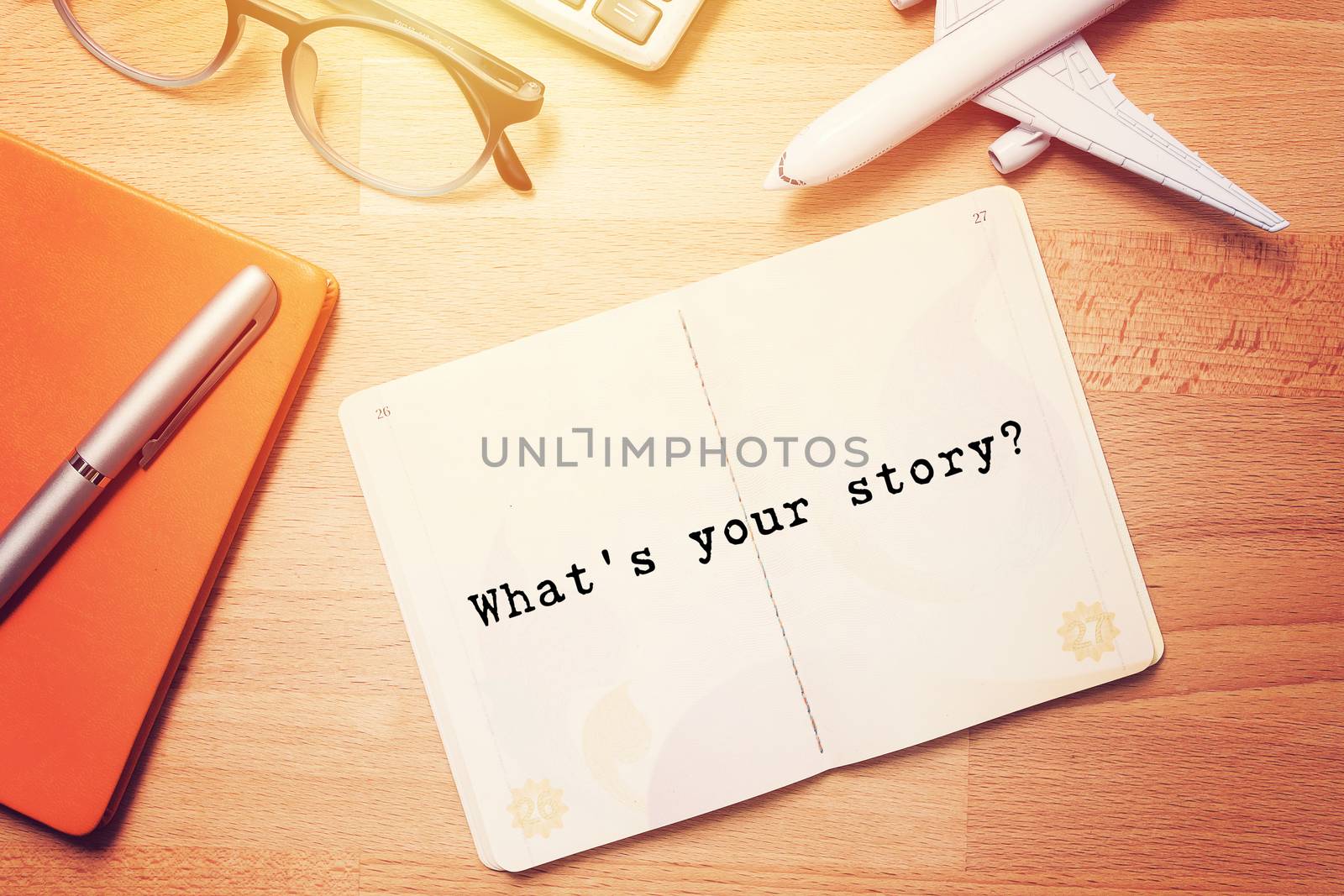 what's your story? notebook with text at blank page on wooden background with glasses and plane model