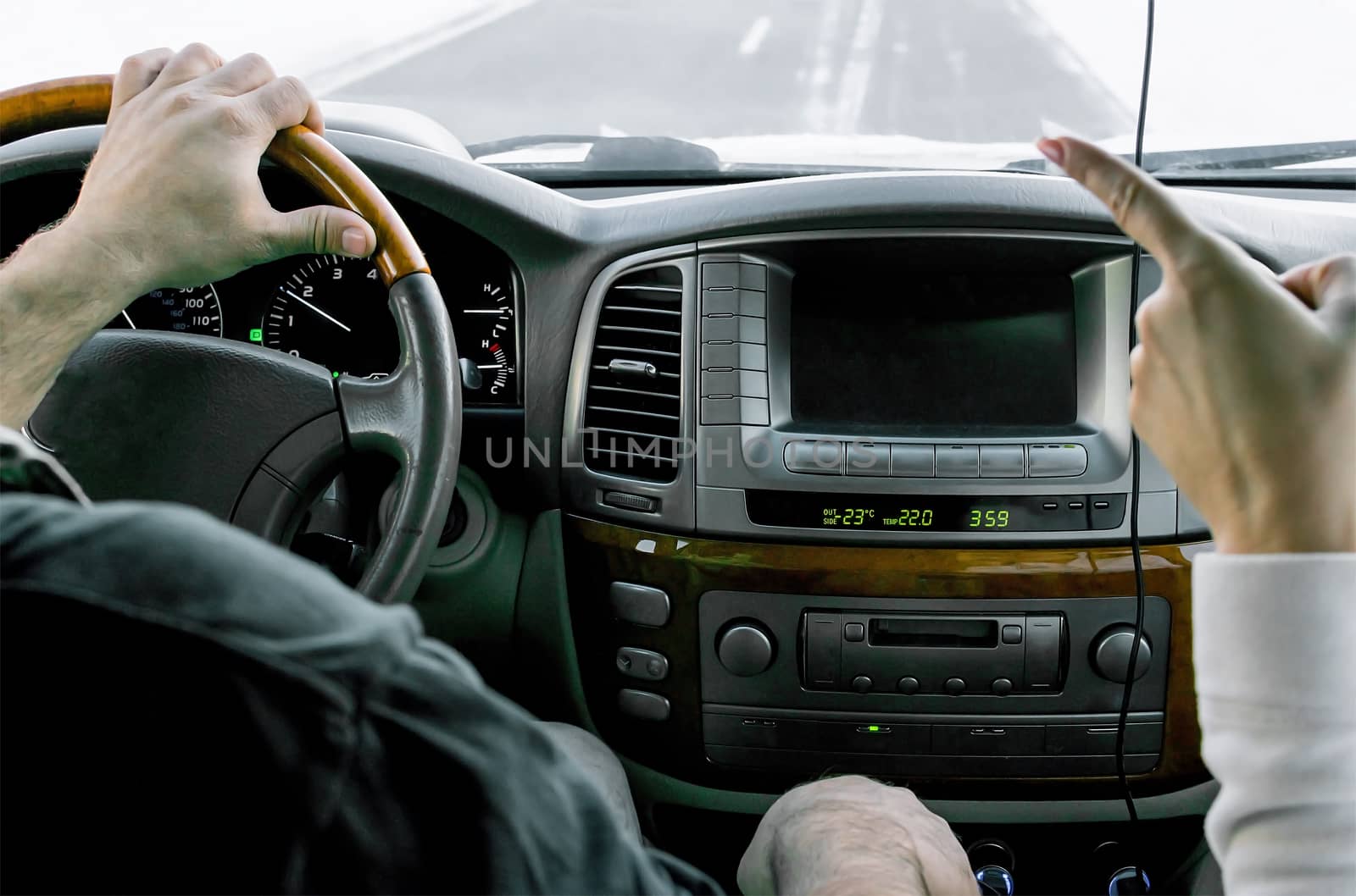 Hand of the girl, points a finger to the man, driver, at the moment when he is driving a car, in the winter, in the snow-covered mountainous terrain on a slippery road by jk3030