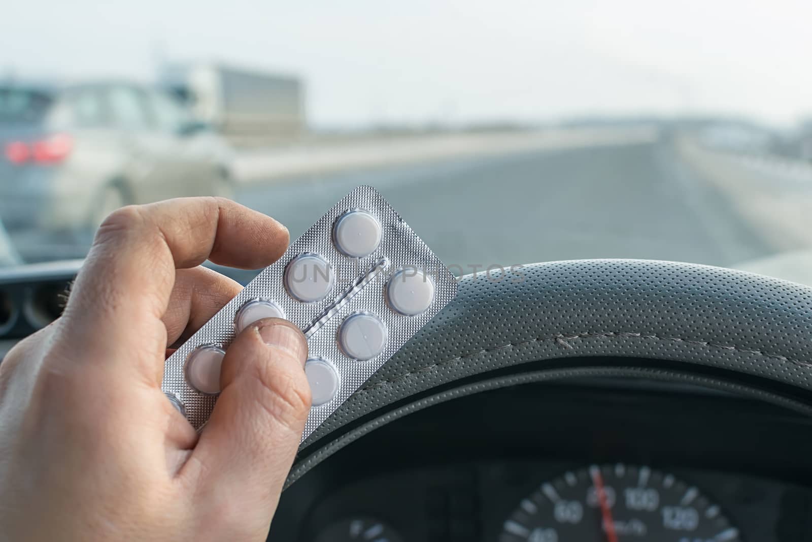 driver hand holding a bag of pills while driving on the highway