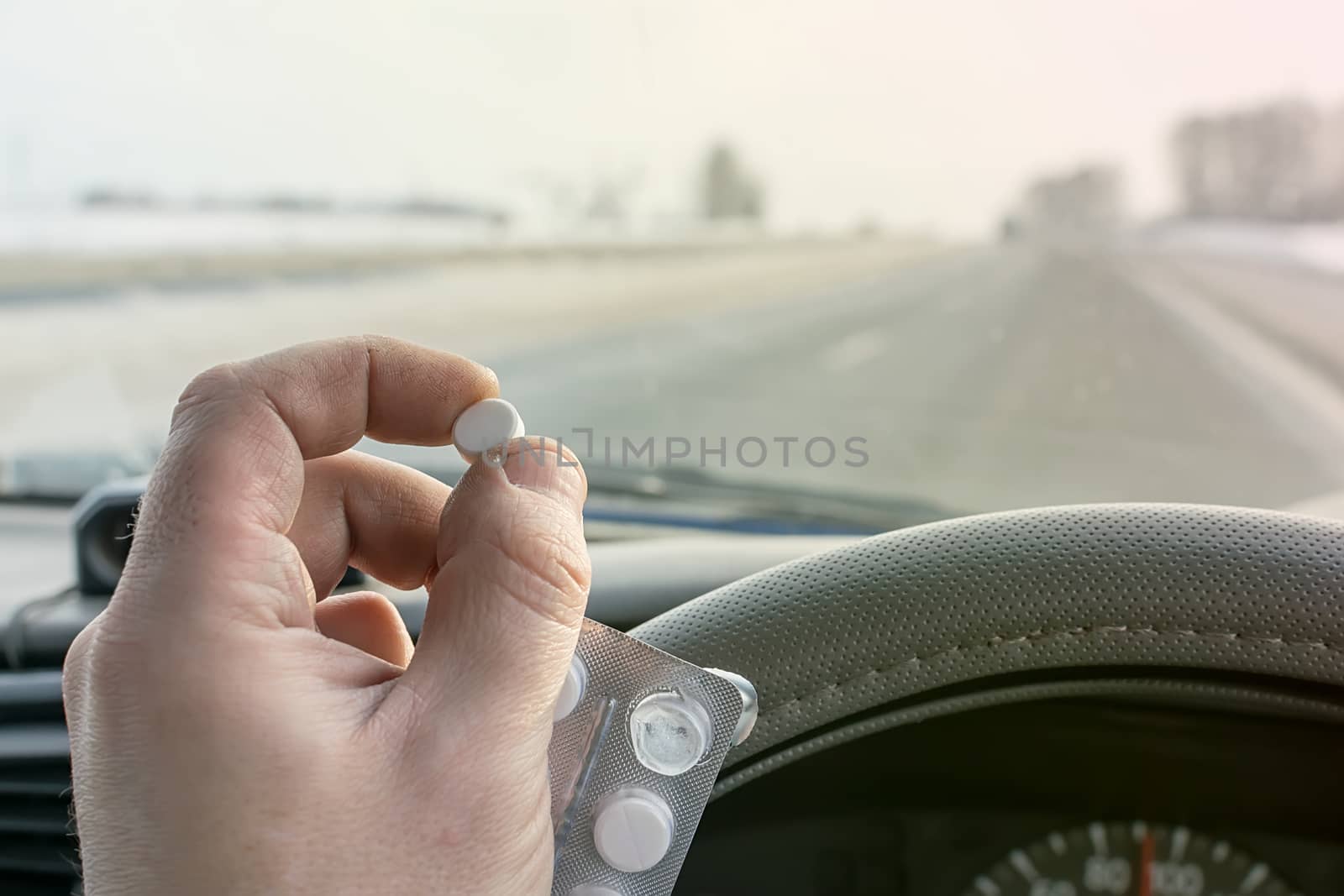 driver hand holding a bag of pills while driving on the highway