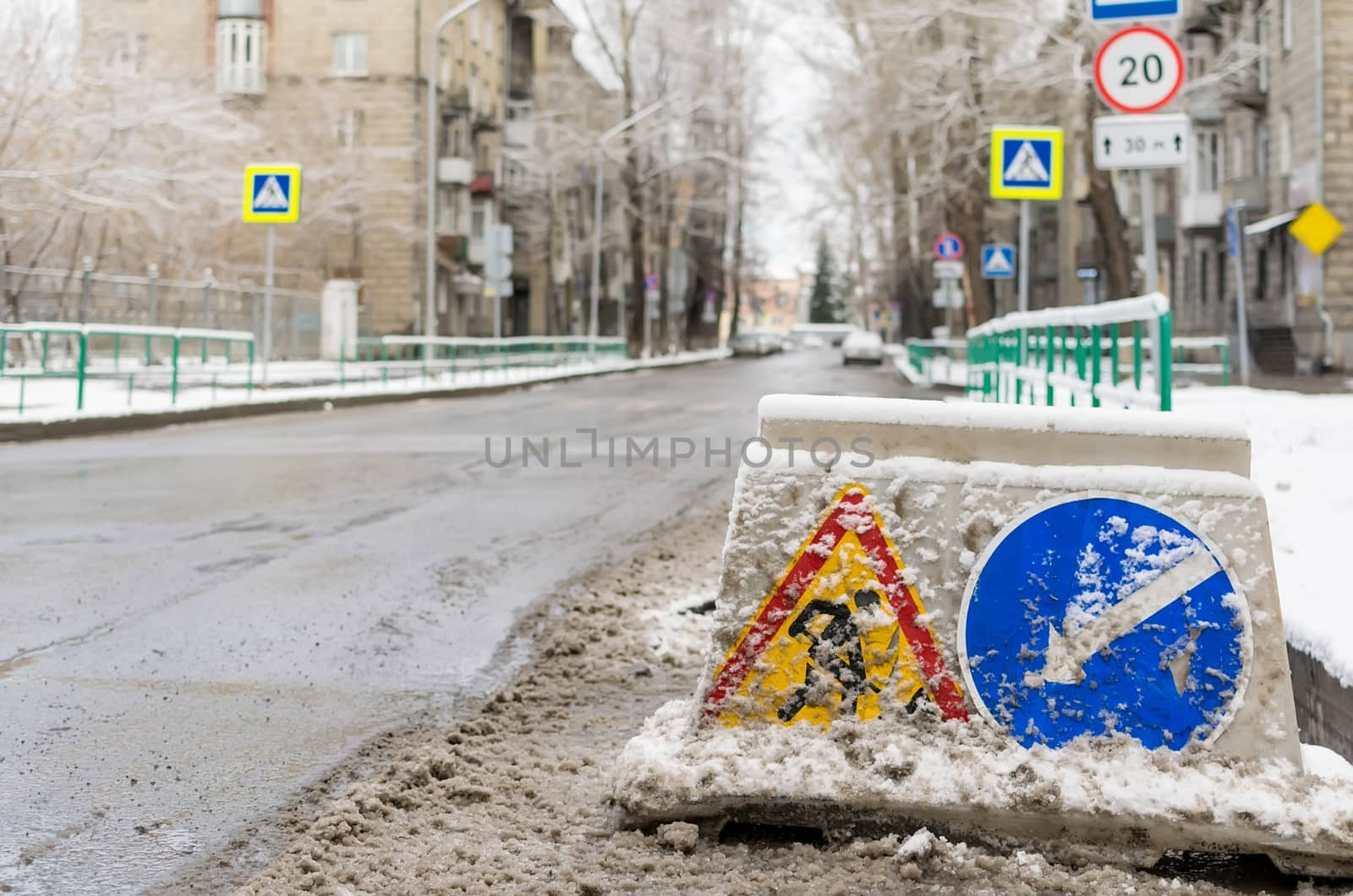 snow-swept road sign, road repair, stands on the roadway of the city street