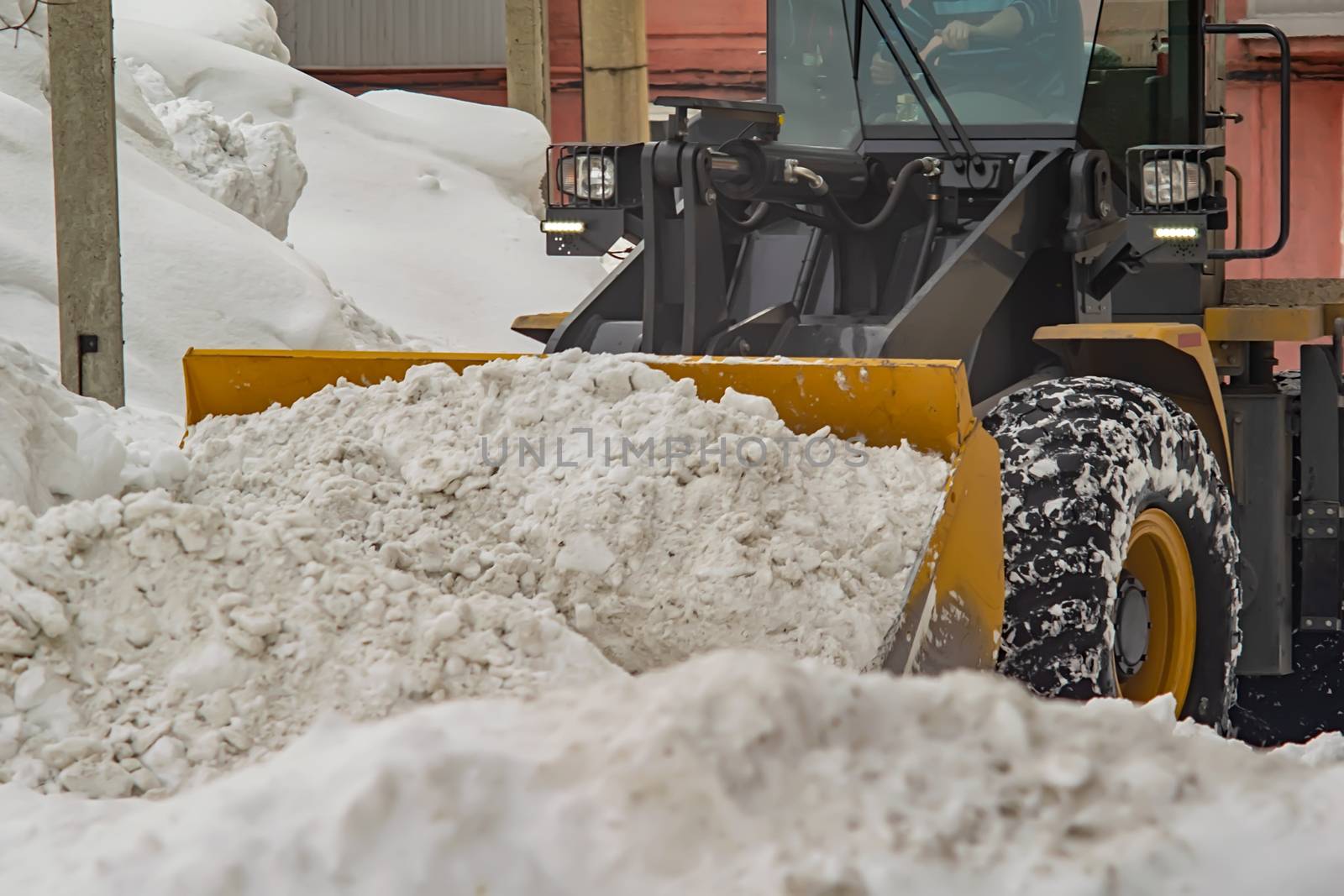 tractor, grader removes a pile of snow in the yard of a residential building by jk3030