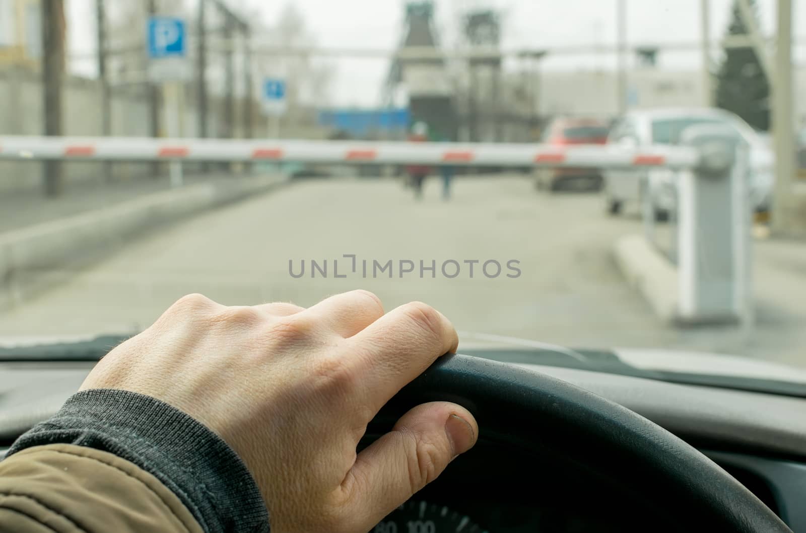 Close-up, the hand of the driver of the car on the background of a closed barrier to enter the Parking lot of the protected object