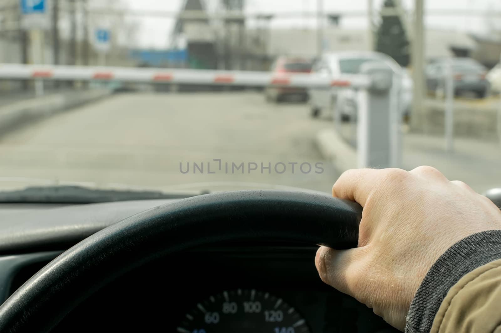 Close-up, the hand of the driver of the car on the background of a closed barrier to enter the Parking lot of the protected object