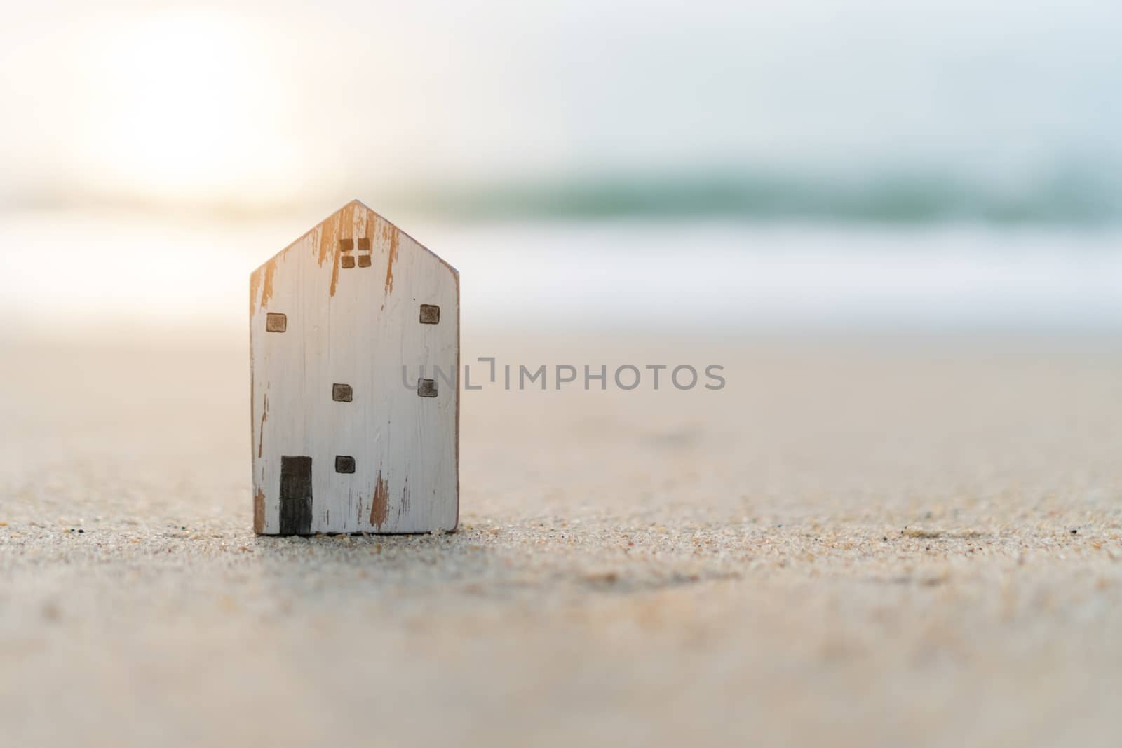 Model of a little house on sand with nature beach background. Dream life concept.