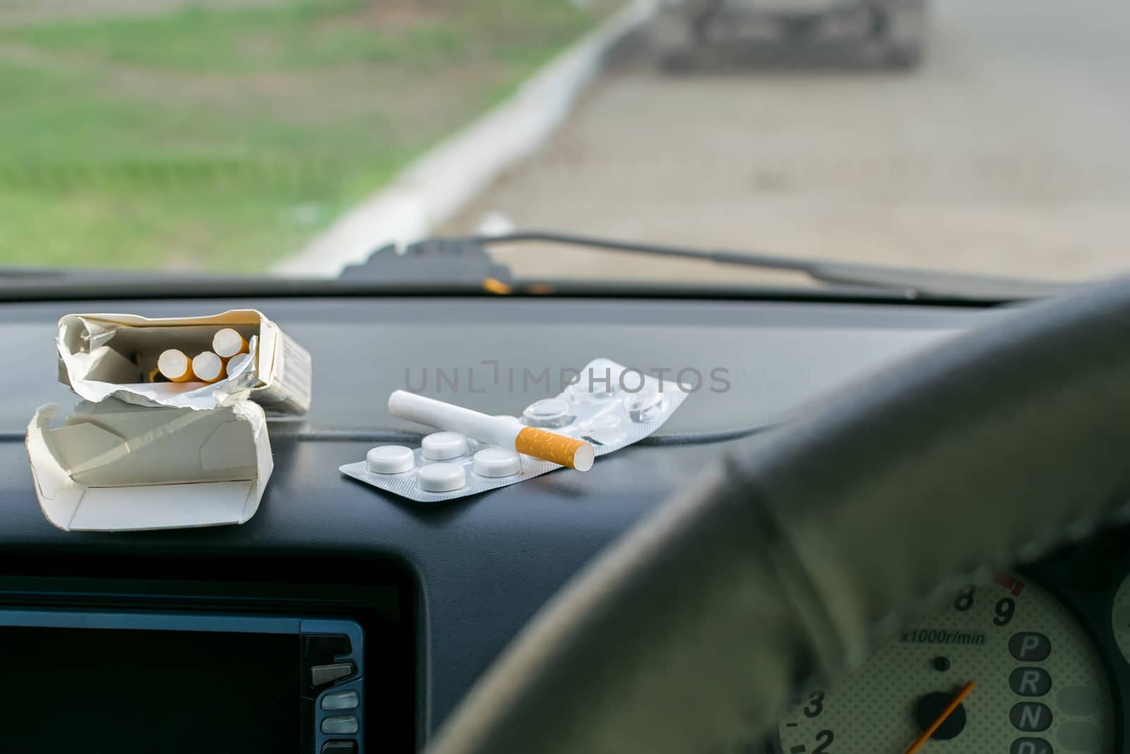 on the panel of the vehicle are cigarettes and pack of pills