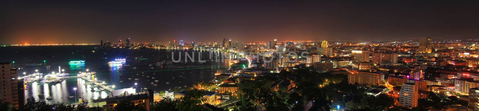 panorama view of pattaya city bay view with building and city night light , boat at dock port. night scene of pattaya city from view point by asiandelight