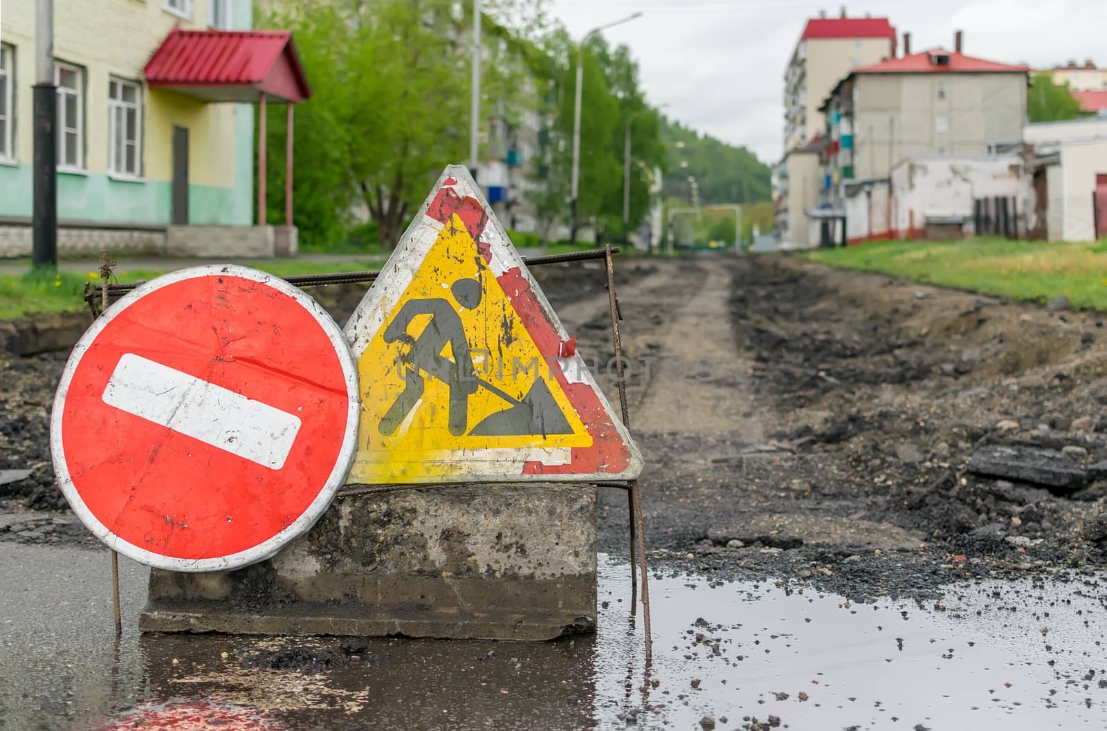road sign, detour, road repair on the background of the road and broken asphalt covering on the urban street