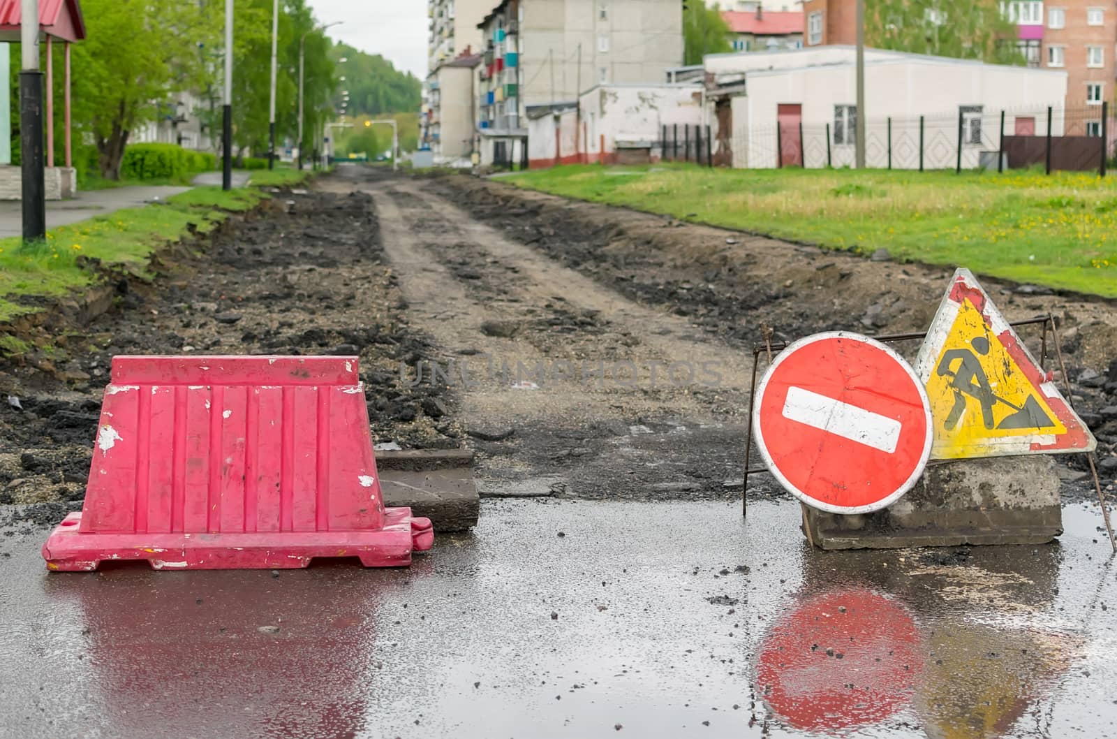 road sign, detour, road repair on the background of the road and broken asphalt covering on the urban street