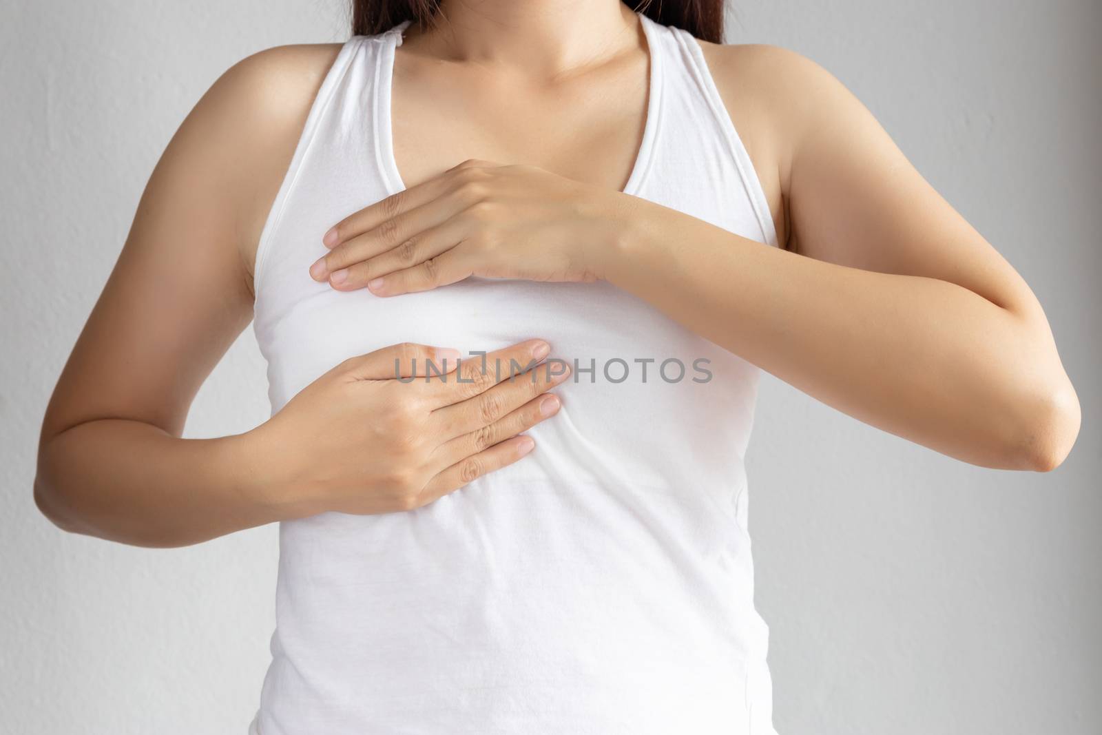 woman in white vest use her hand for breast cancer self check. healthy woman lifestyle medical awareness concept by asiandelight