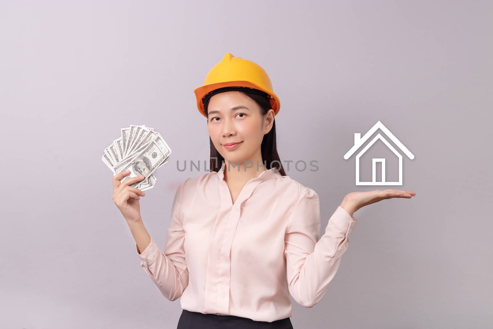 loans for real estate concept, woman with yellow helmet holding banknote money in hand and white logo home icon in another hand