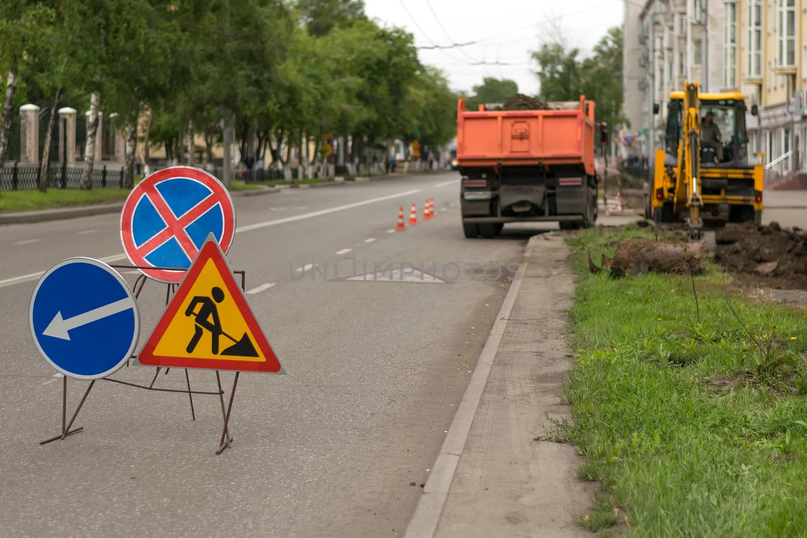 Road signs, detour, road repair on street background, truck and excavator digging hole