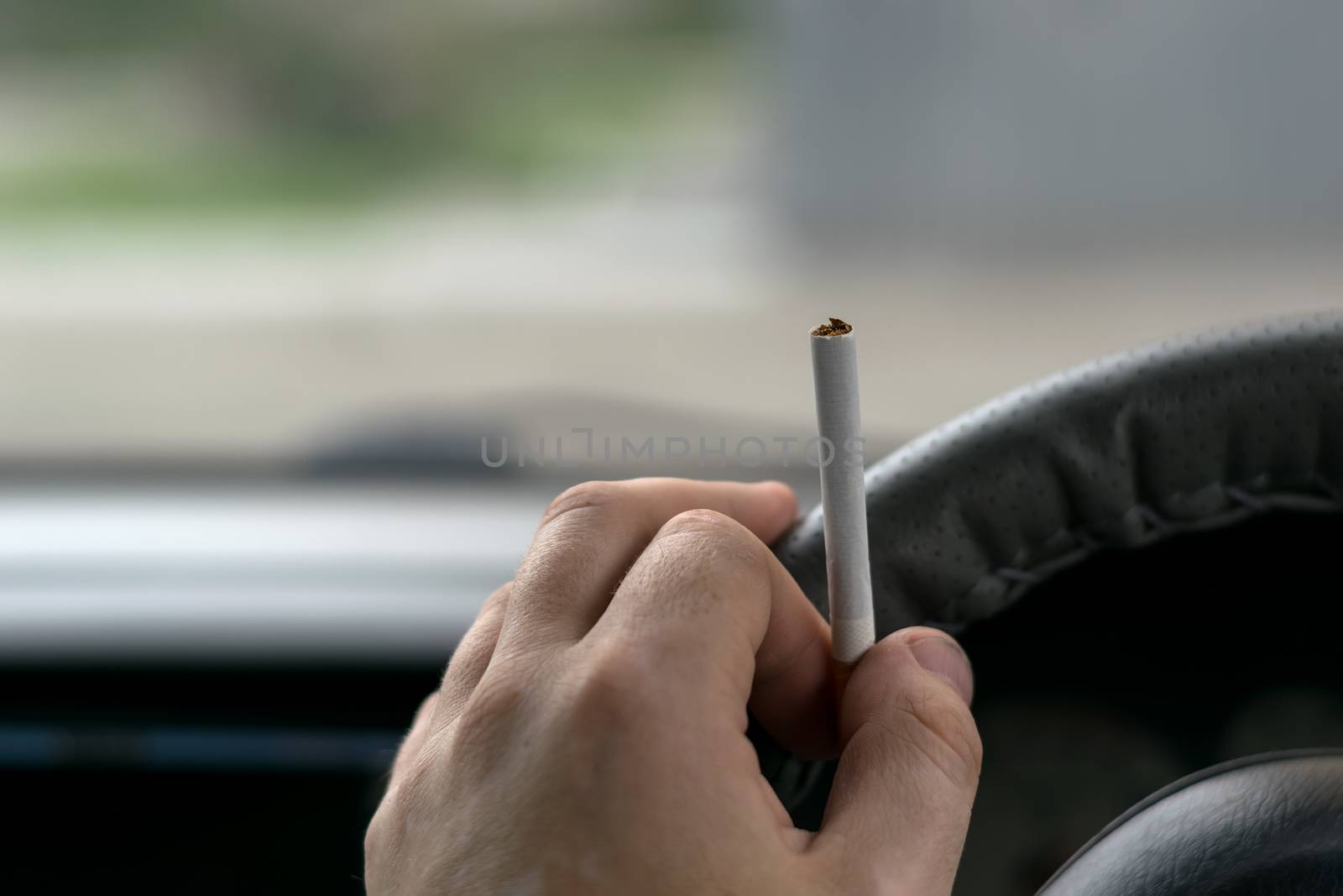 close-up, the hand of the driver of the car with skin disease "vitiligo" holds a cigarette