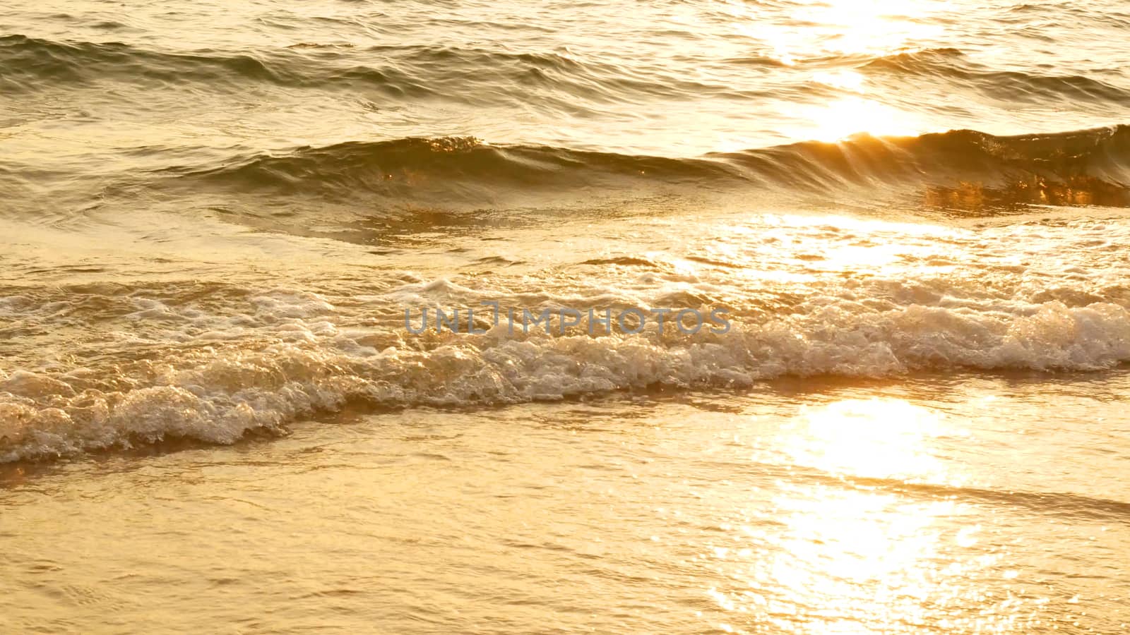 amazing sunset over the tropical beach. ocean beach waves on beach at sunset time , sunlight reflect on water surface. beautiful evening nature sea background.