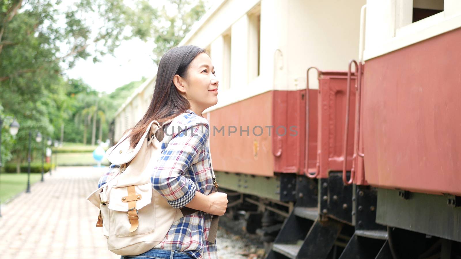 happy Asian tourist woman with backpack walk to the train at railway station, begin travel alone. travel in Asia by vintage train. leisure tourist travelling by train transportation