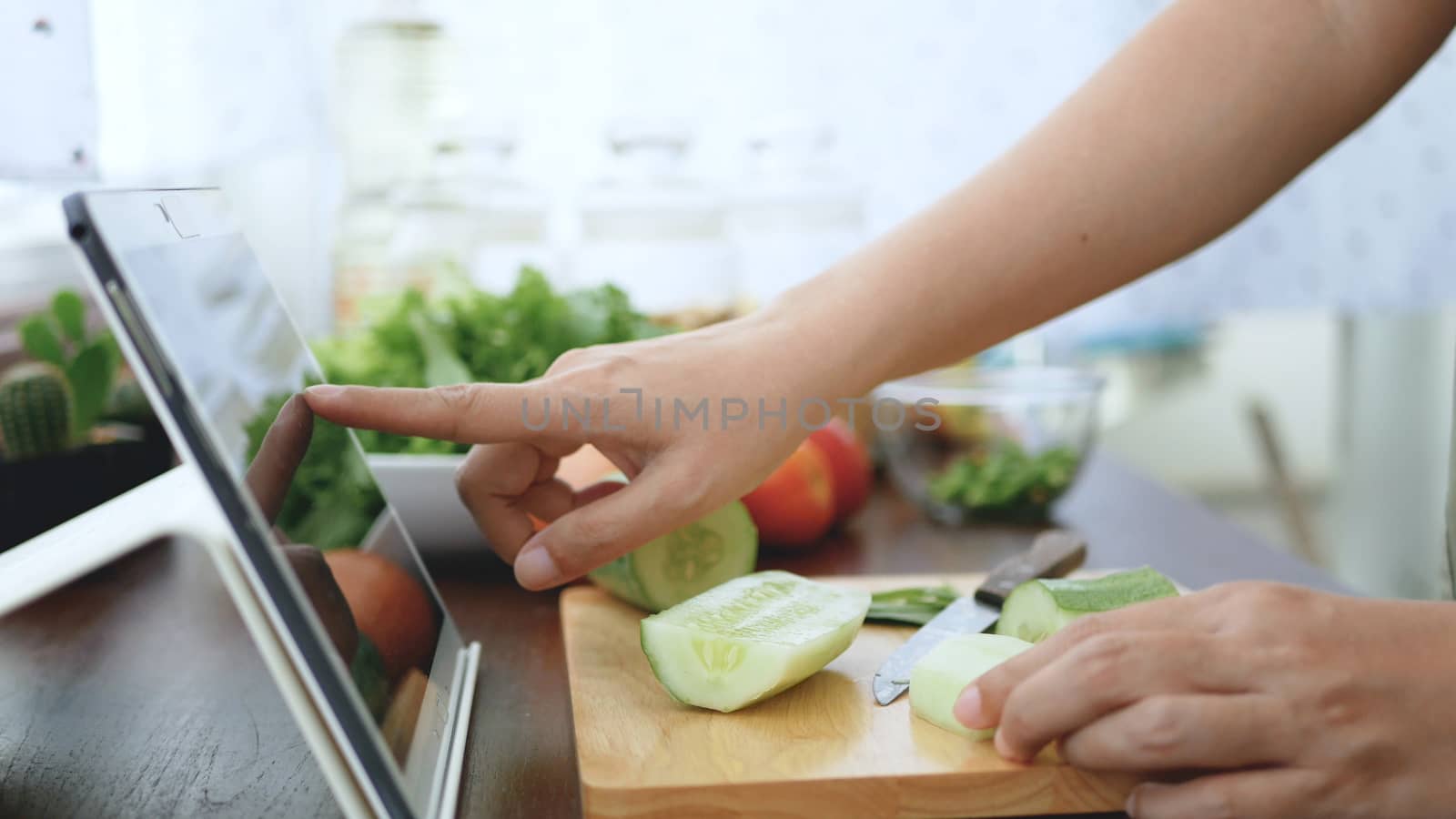 Asian woman use finger slide on tablet screen prepare ingredients for cooking follow cooking online video clip on website. cooking content on internet technology for modern lifestyle concept