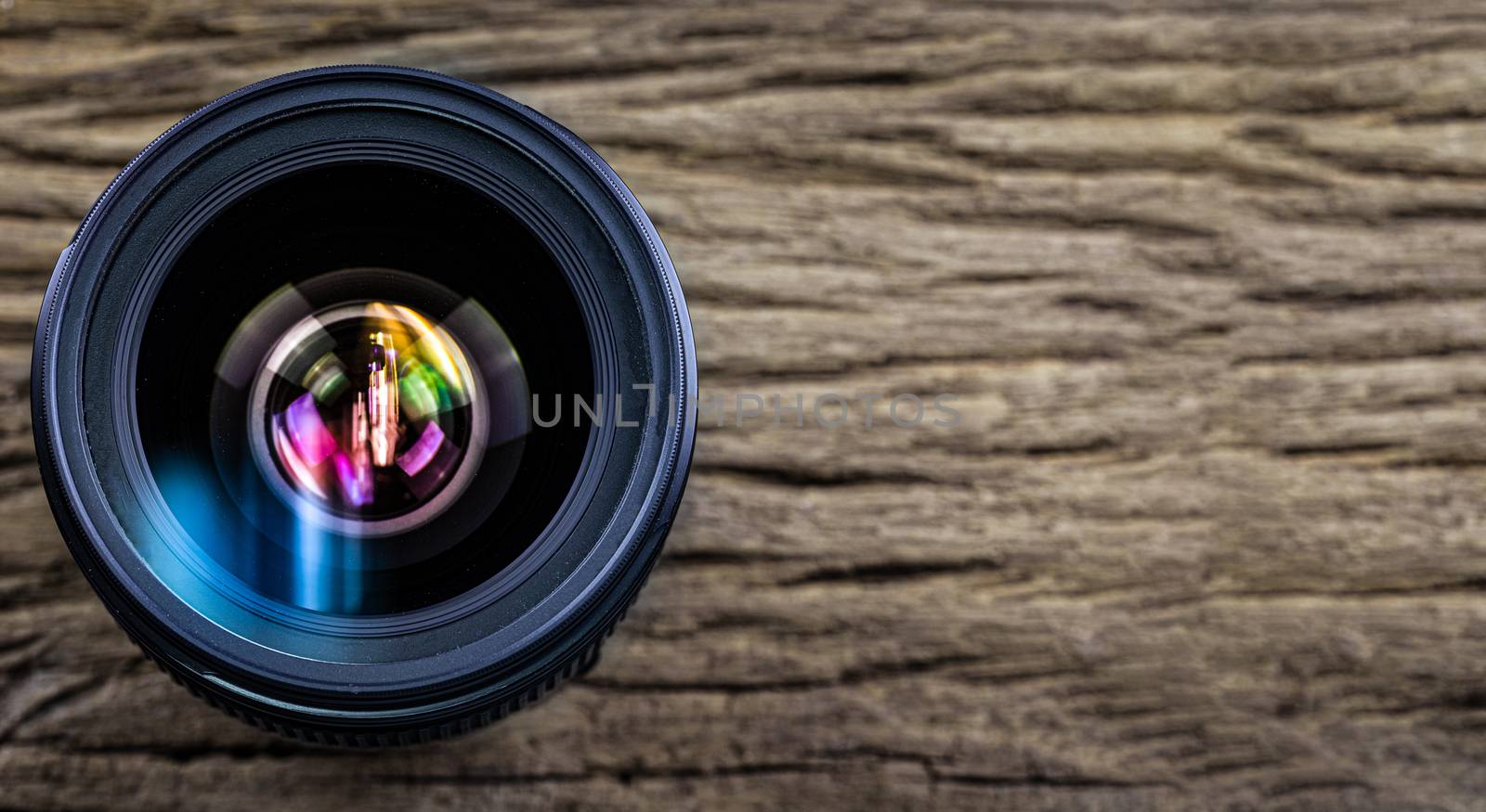 Camera lens on wood grain background by Natstocker