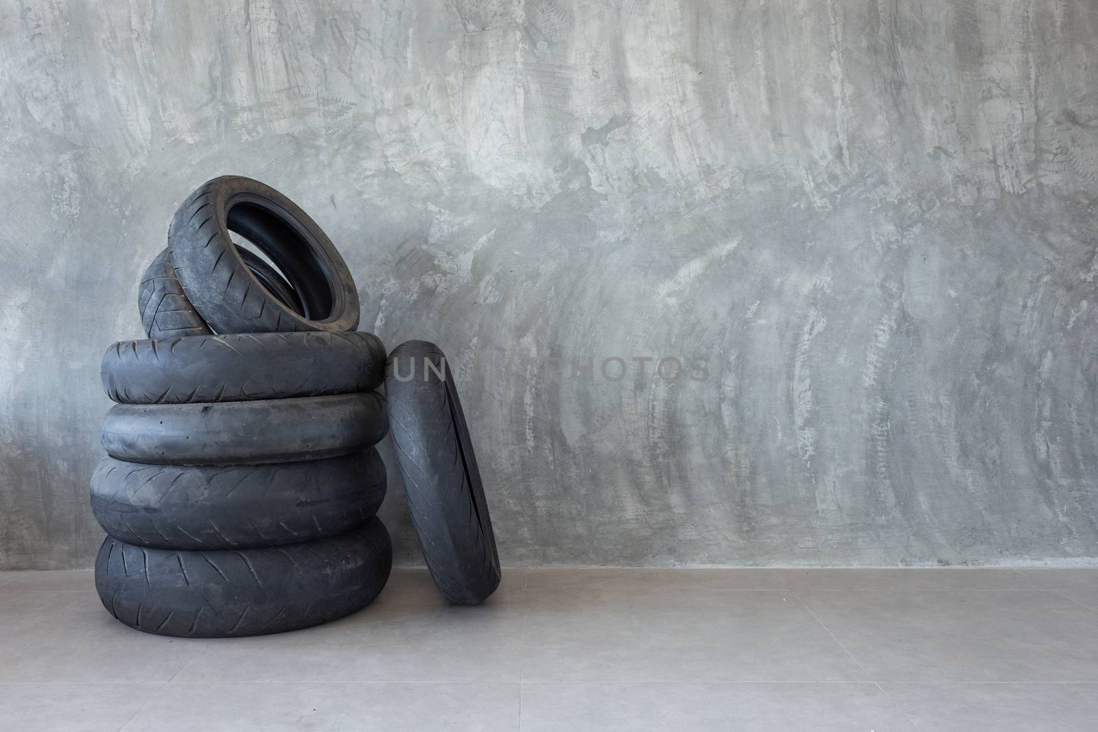 Old motorcycle tire on Bare cement wall  by Natstocker