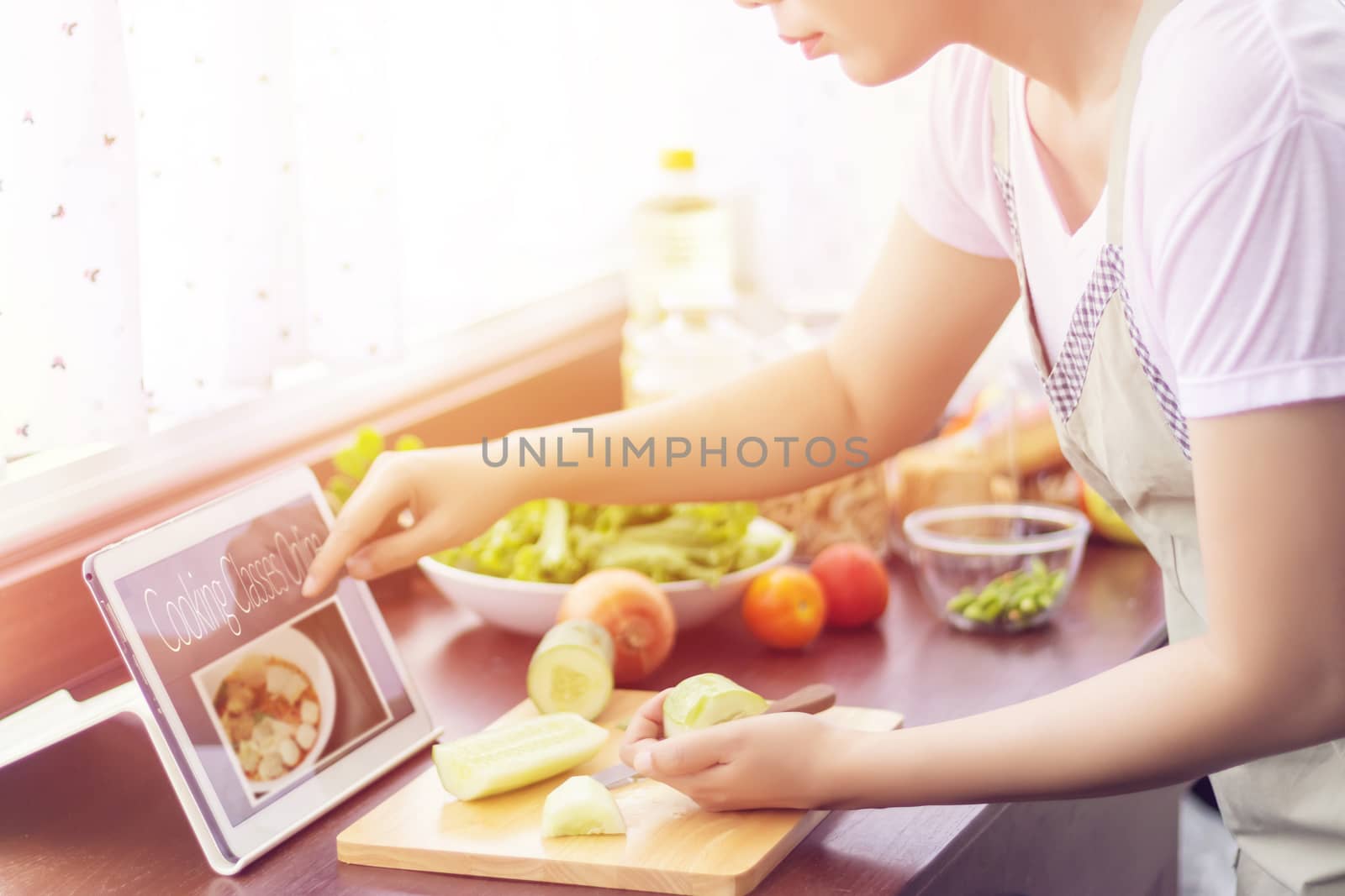 Asian woman prepare ingredients for cooking follow cooking class online course on website via tablet. cooking content on internet technology for modern lifestyle concept