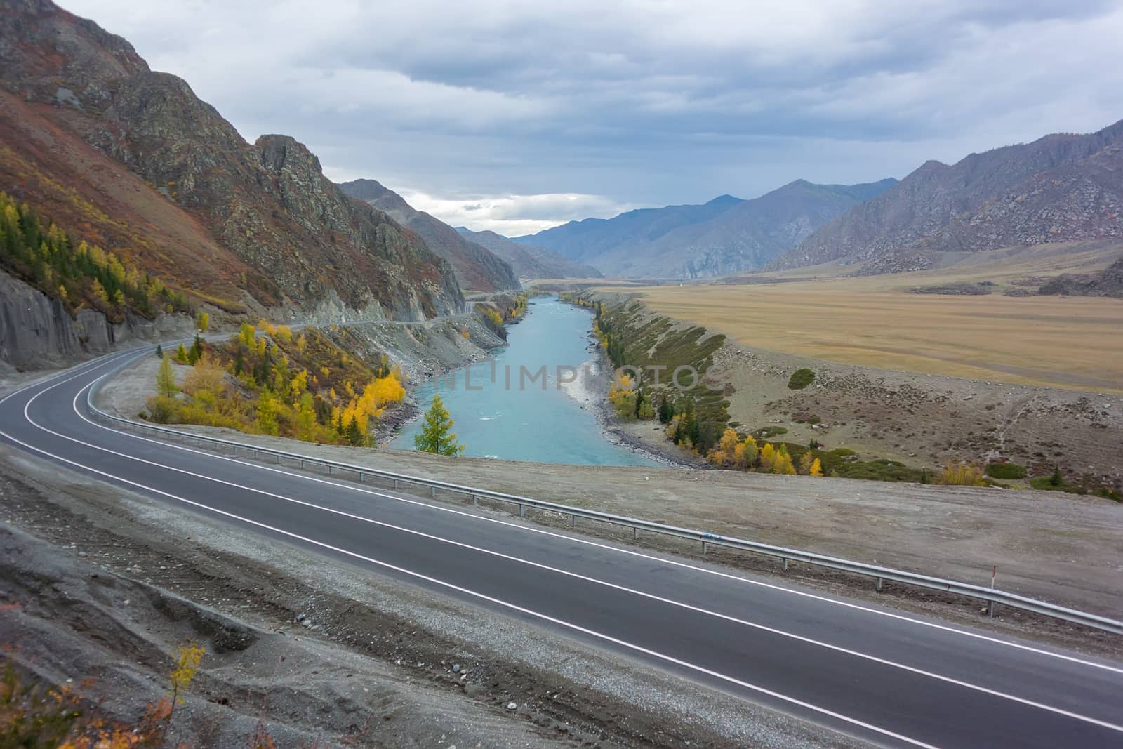 autumn landscape of asphalt road in a mountain valley with a turquoise river