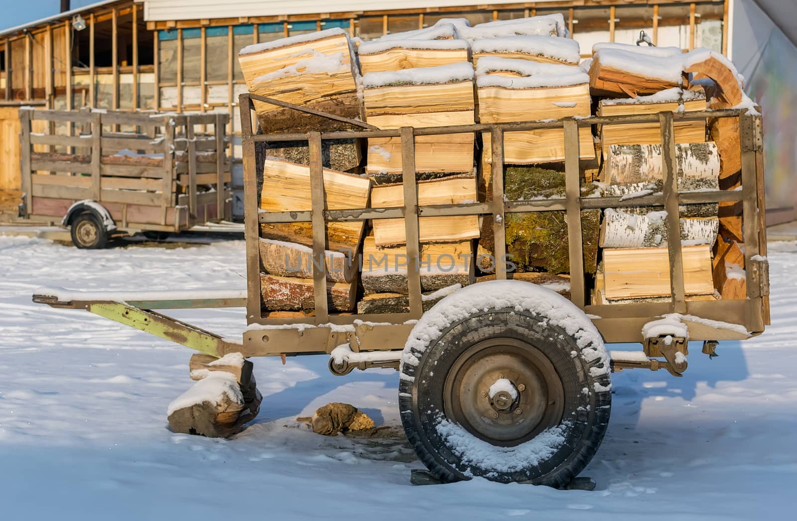 Cart, trailer, wagon for transportation of firewood is for sale in the countryside in the snow in winter