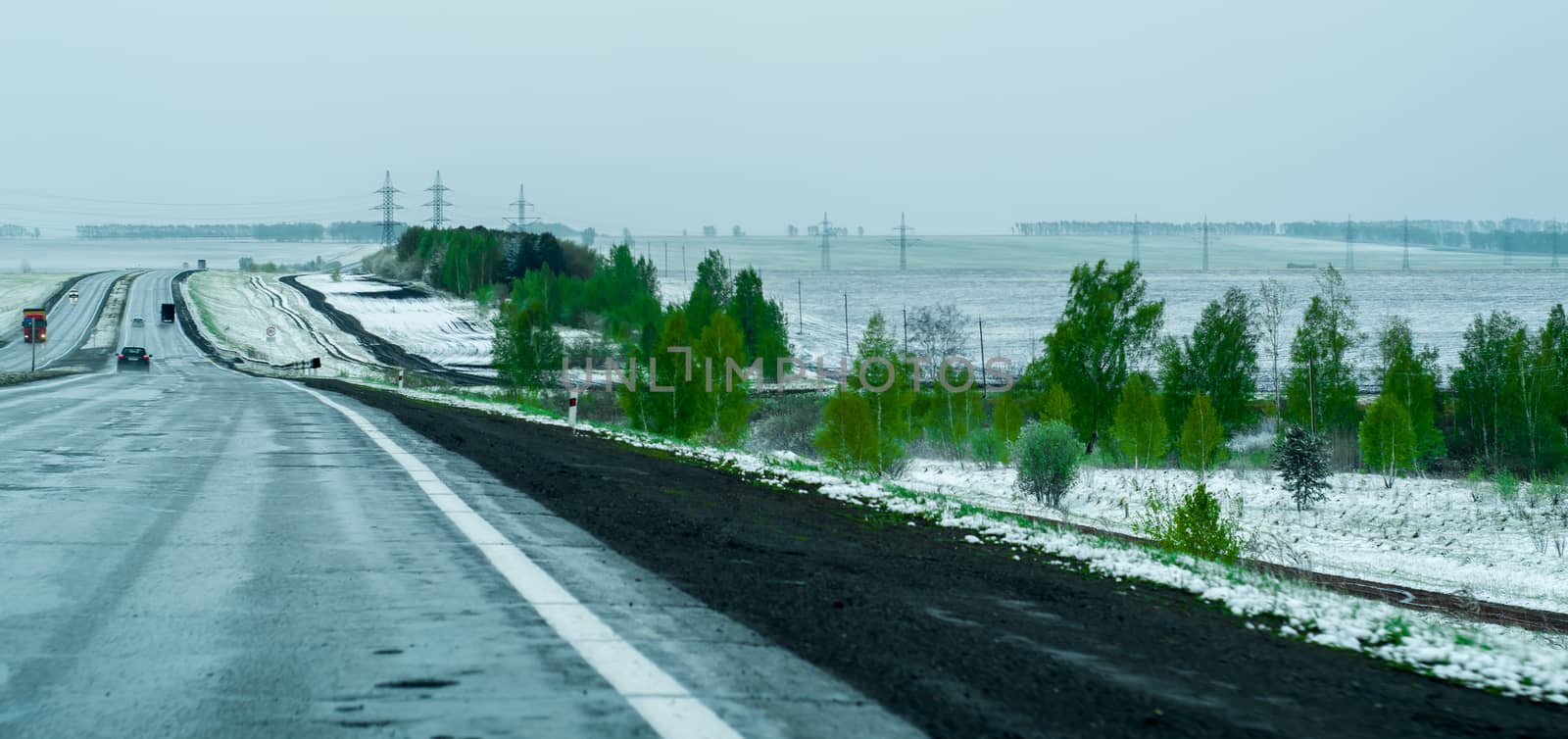 landscape suburban track with snow in early summer. Twilight and fog. Dangerous road