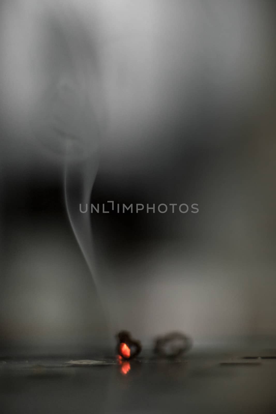 The smoke of a cigarette draws sinuous shapes in the air.