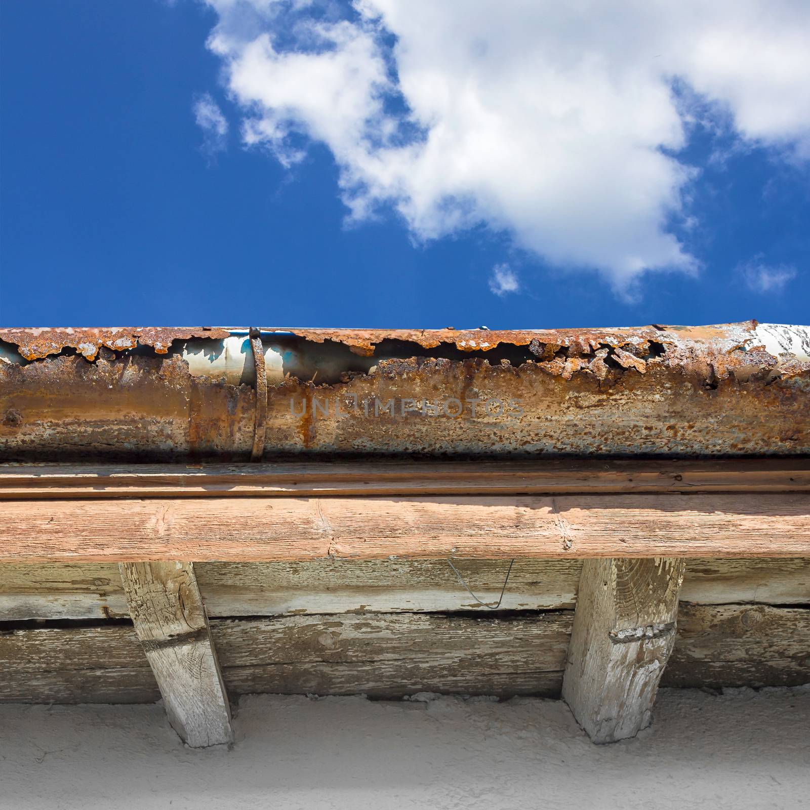 Old gutter against blue sky by germanopoli