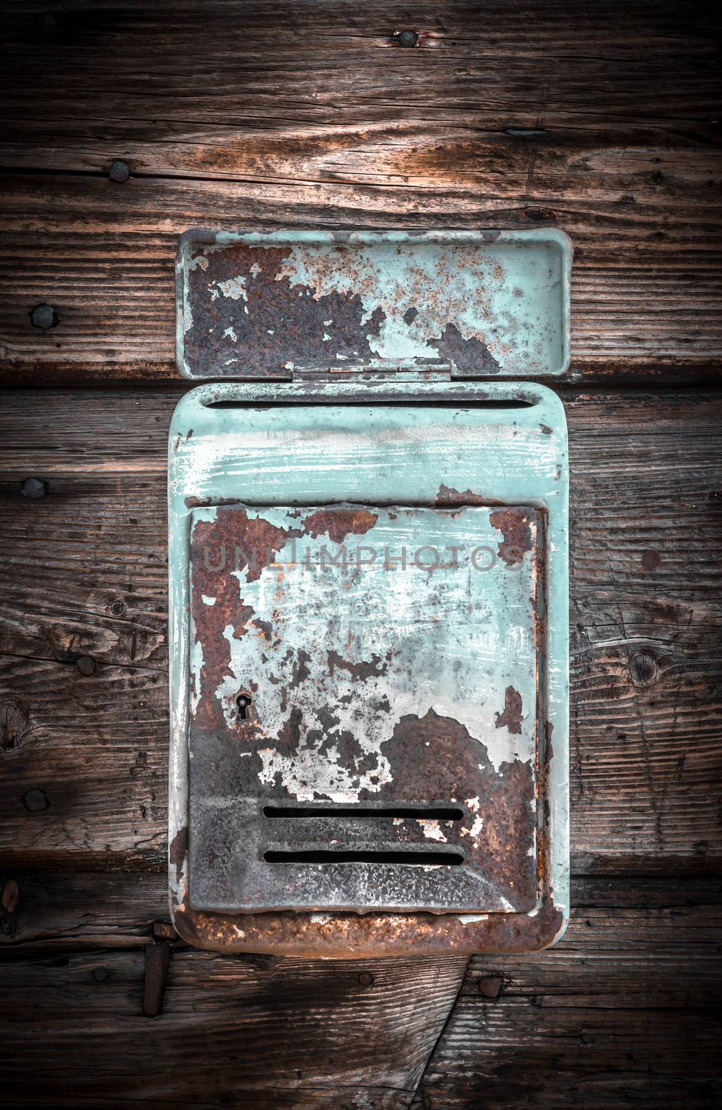 Rusty metal mailbox on the wooden doorway