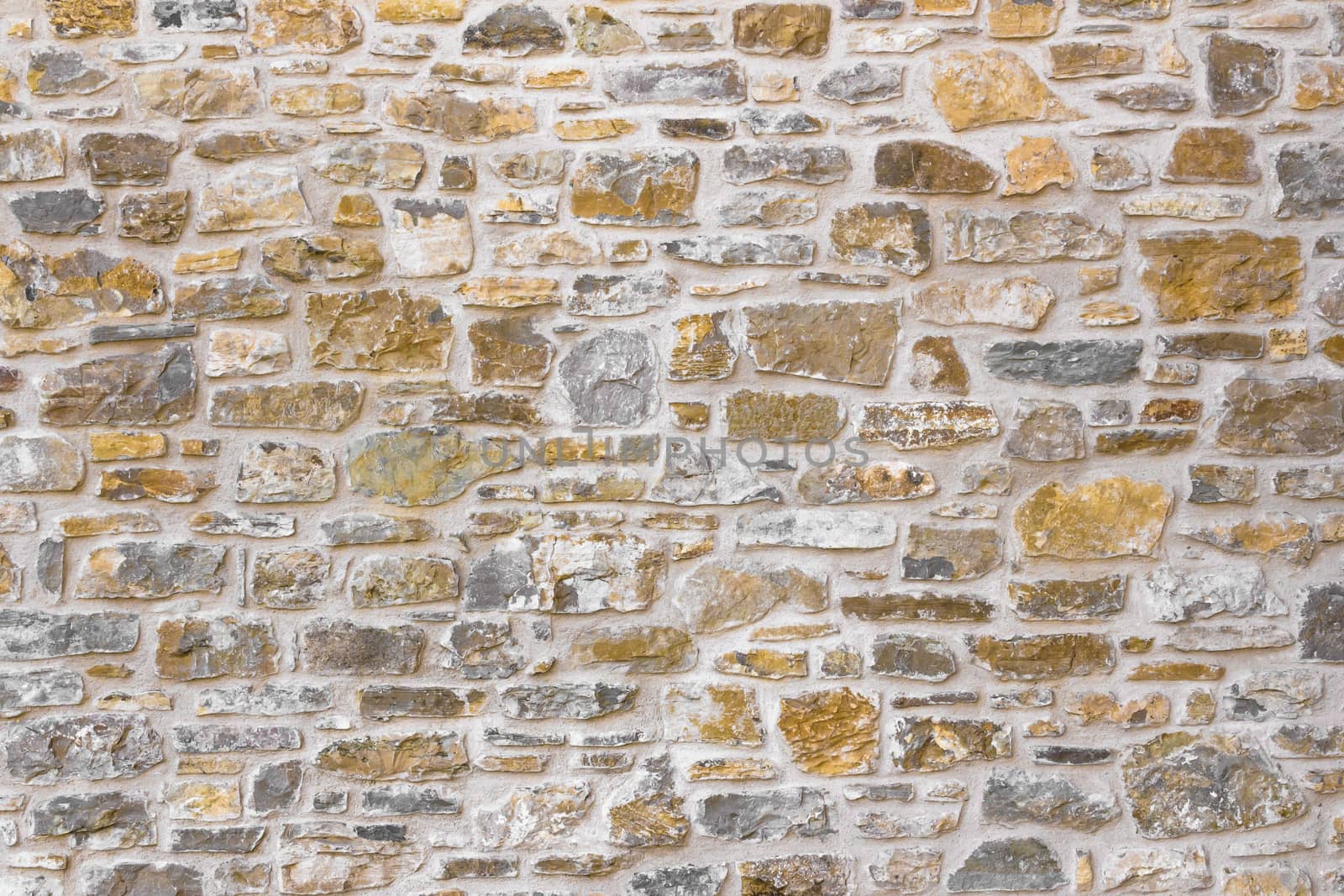 Old irregular golden stone wall, background.