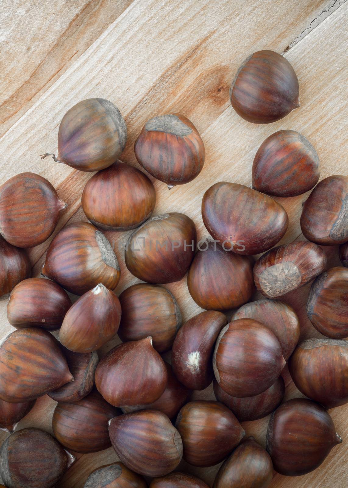 Chestnuts scattered on a wooden table, seen from above