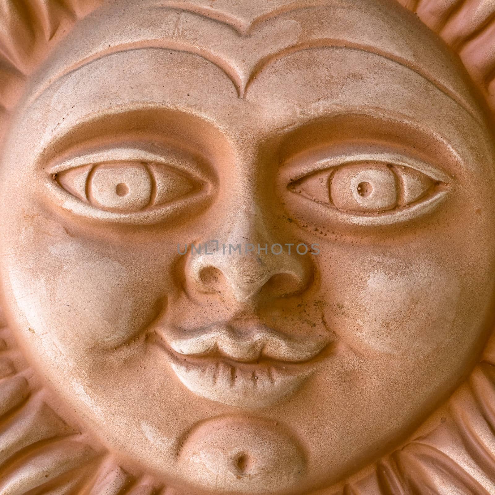 A clay sculpture depicting a smiling sun.