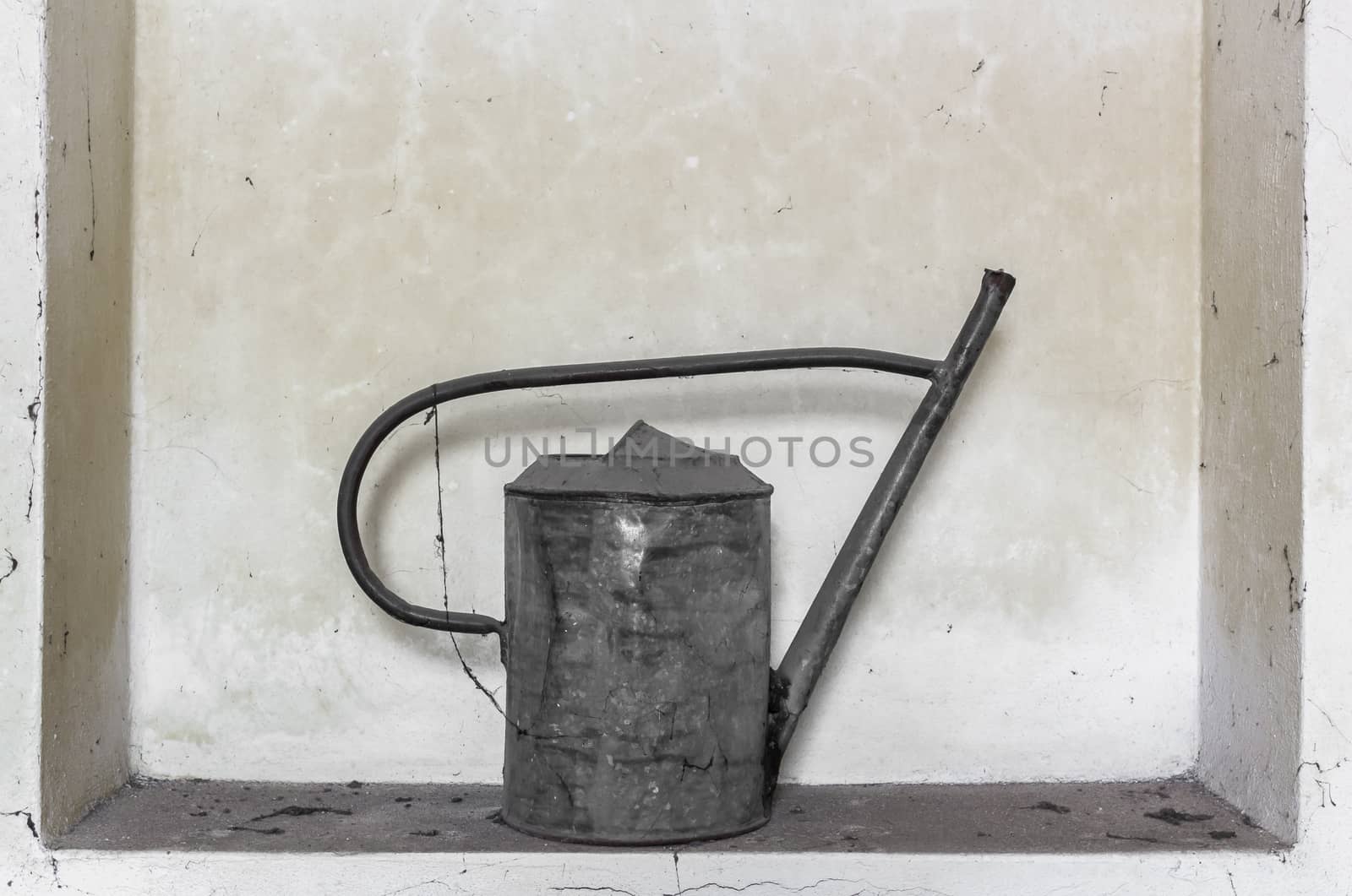 Old watering can abandoned and covered with cobwebs