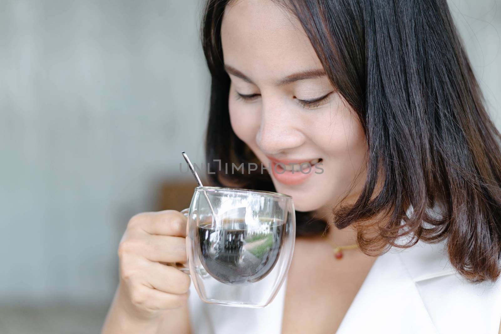Close up woman drinking hot americano coffee from glass with light in the morning, Selective focus