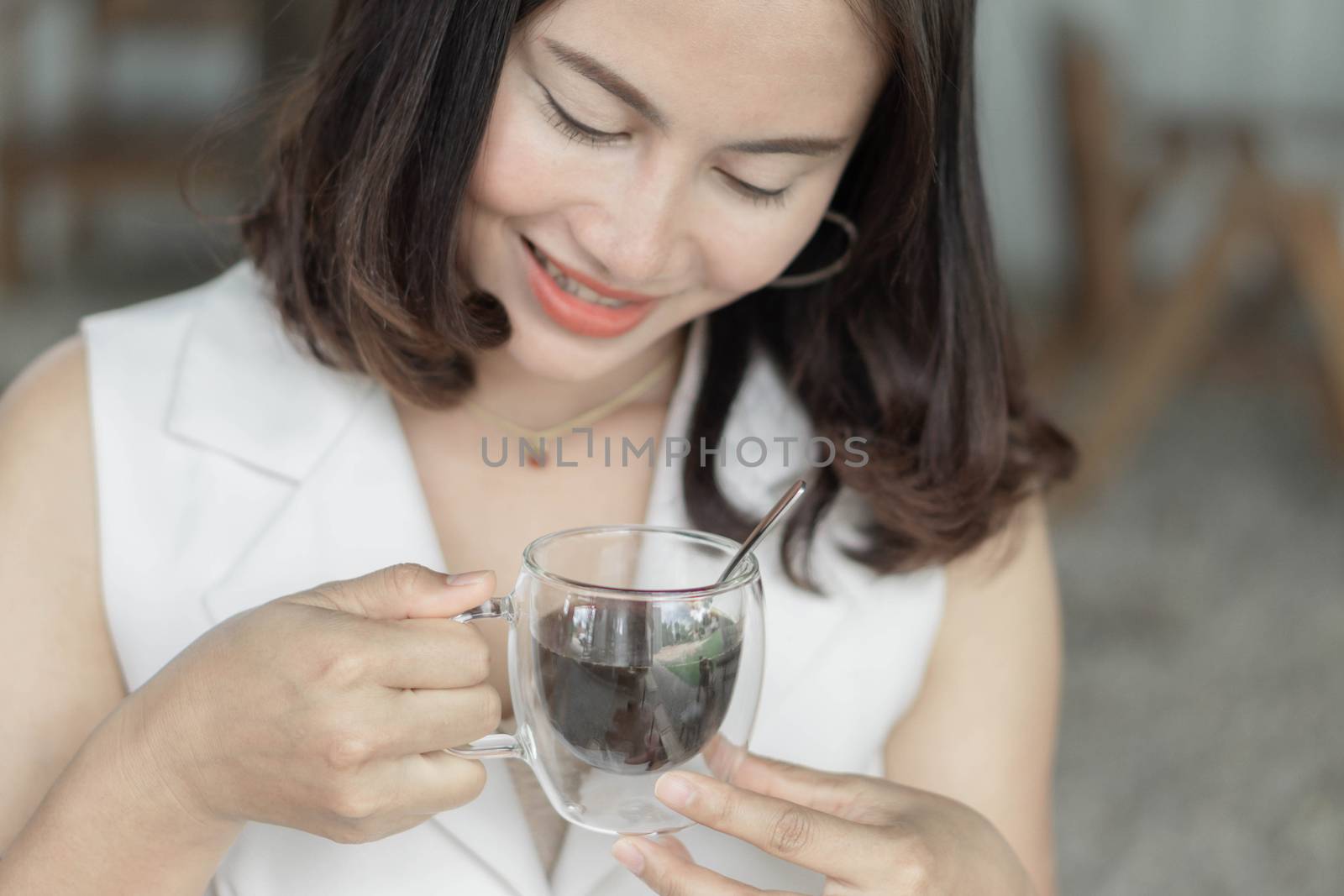 Close up woman drinking hot americano coffee from glass with light in the morning, Selective focus