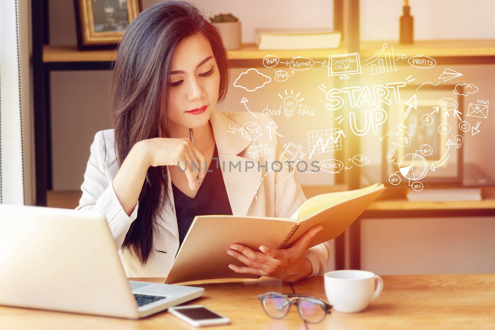 portrait of serious young Asian woman sitting in office with startup business plan in foreground