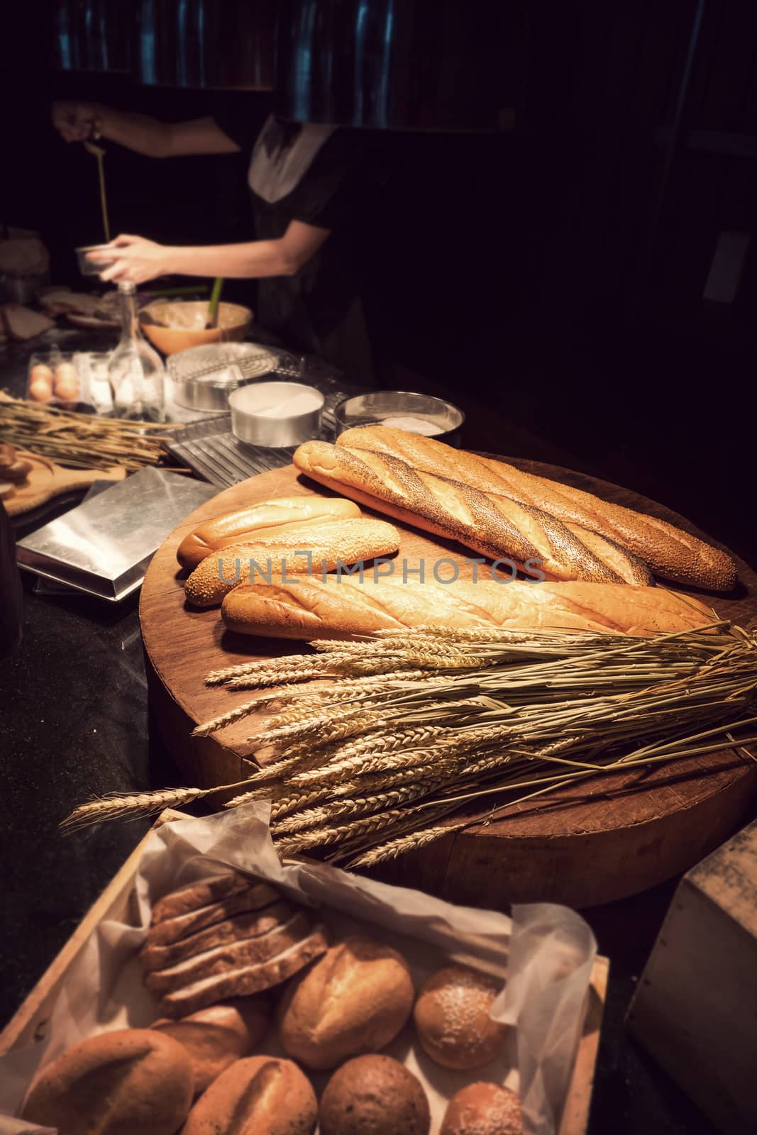 freshly homemade baked traditional bread on wooden table with woman baking bakery at background by asiandelight