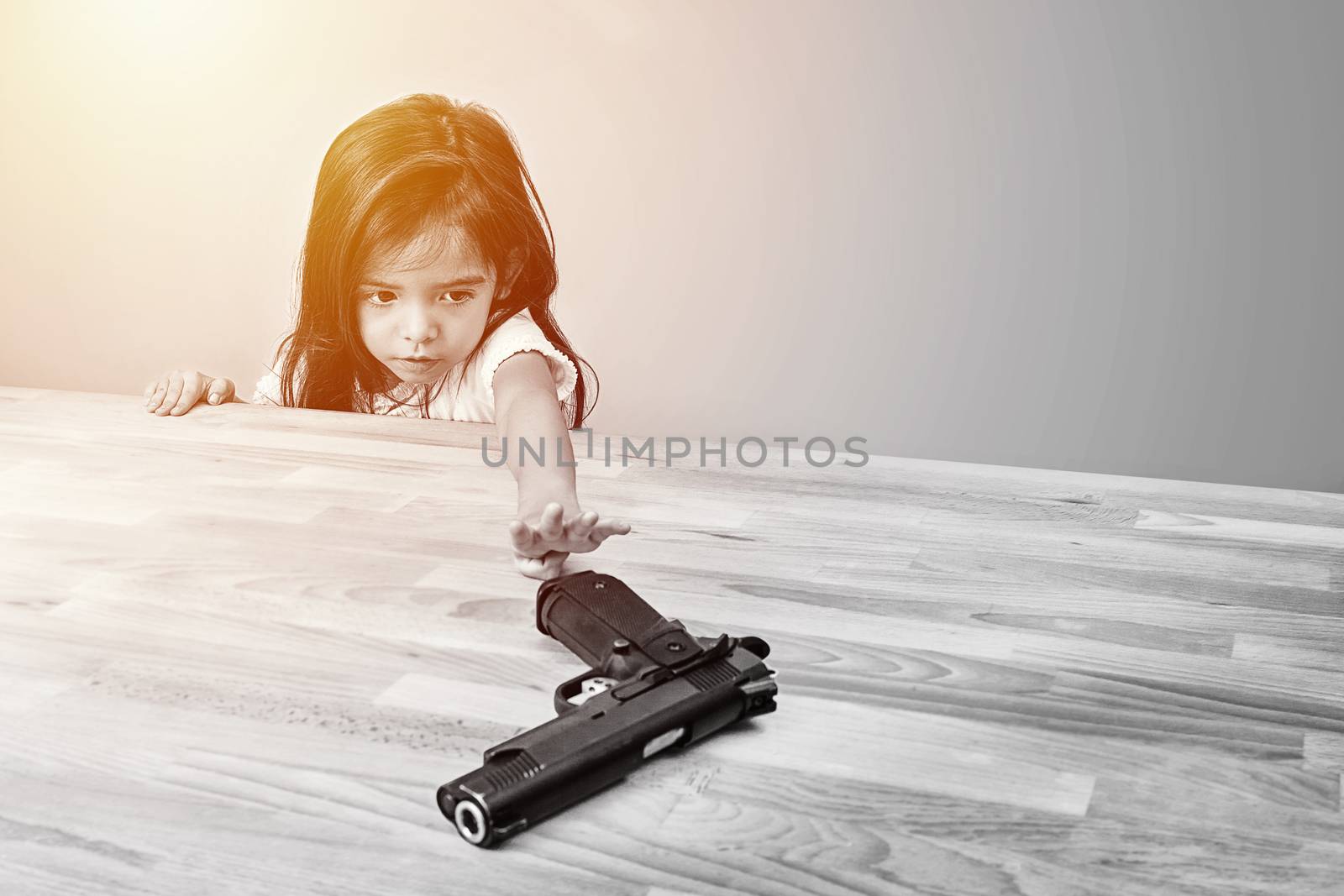 safety and accident in home concept. children try to play parent's gun on table. monotone color