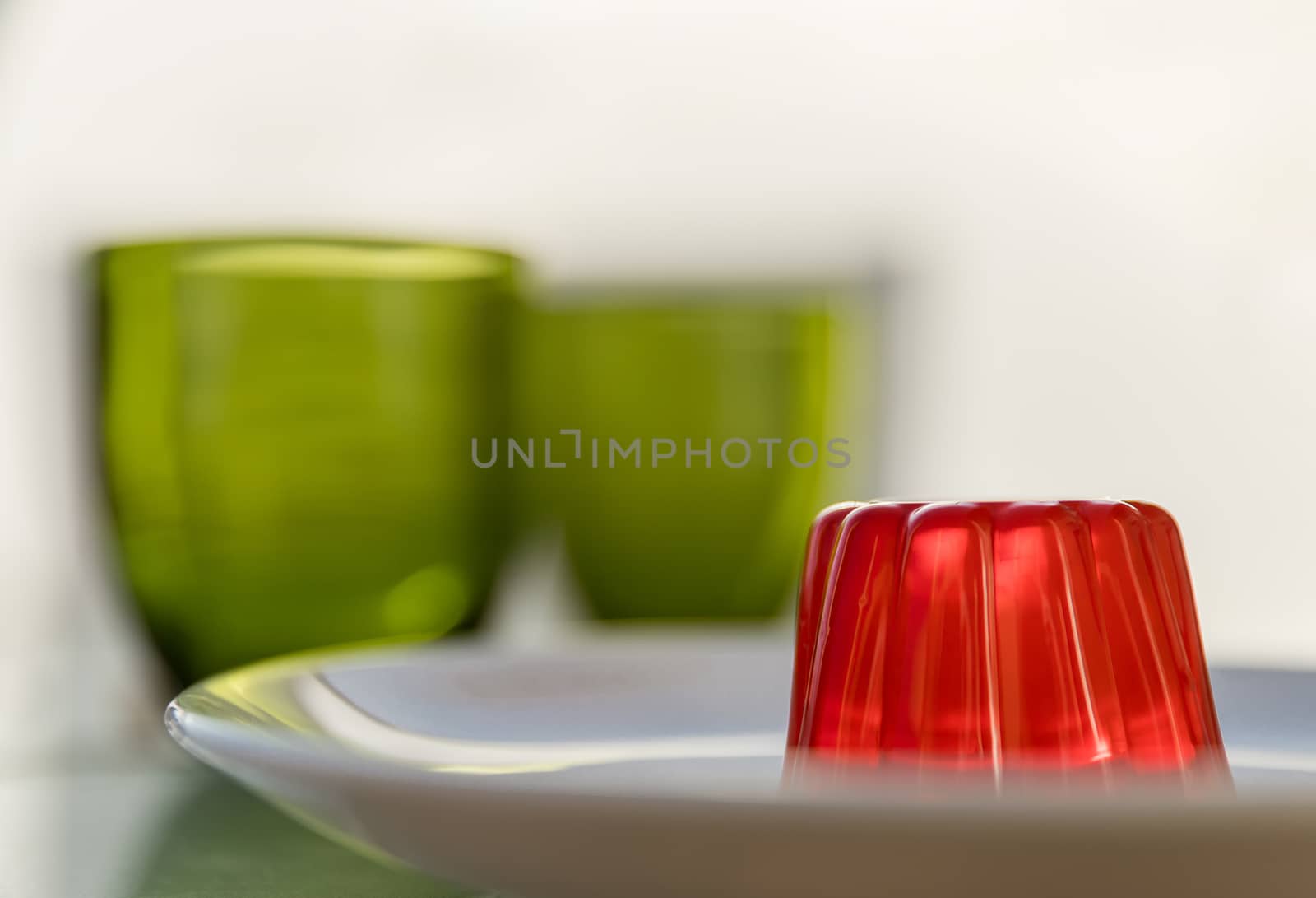 Close-up of a strawberry jelly dessert with a two green glasses in the background