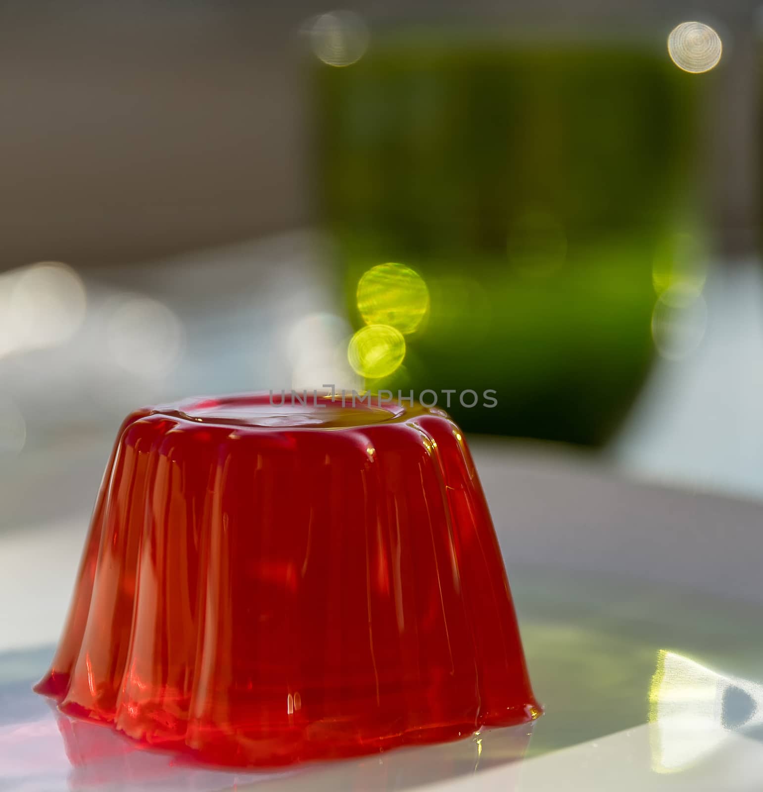 Close-up of a strawberry jelly dessert with a green glass in the background