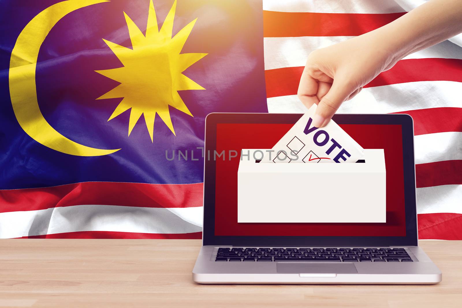 online vote , poll, exit poll for Malaysia general election concept. close up hand of a person casting a ballot at elections during voting on canvas Malaysia flag background.